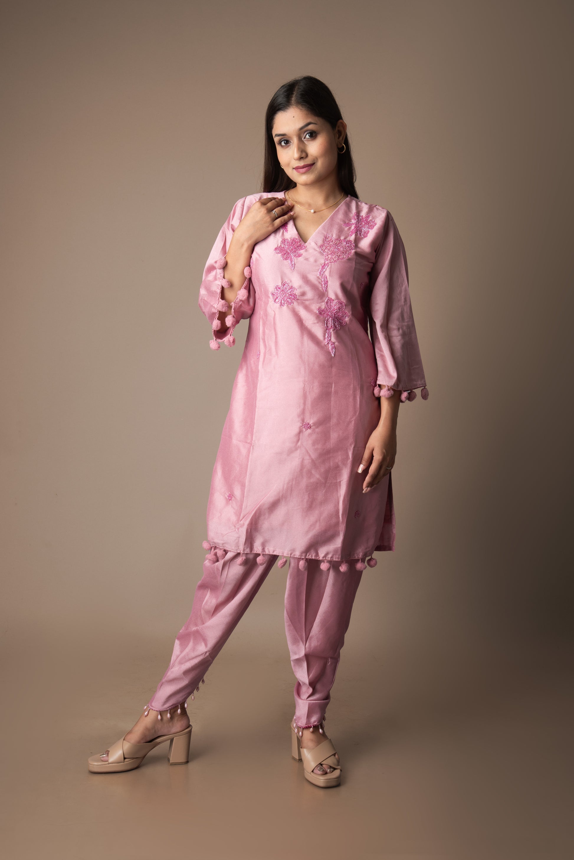 Woman wearing a pink traditional outfit with floral patterns on a brown background