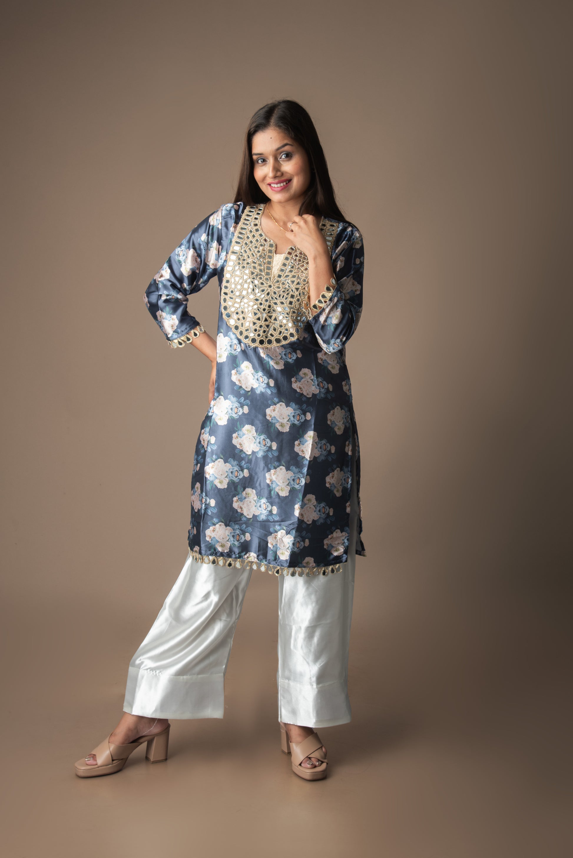 Woman wearing a blue floral kurta with white pants on a brown background