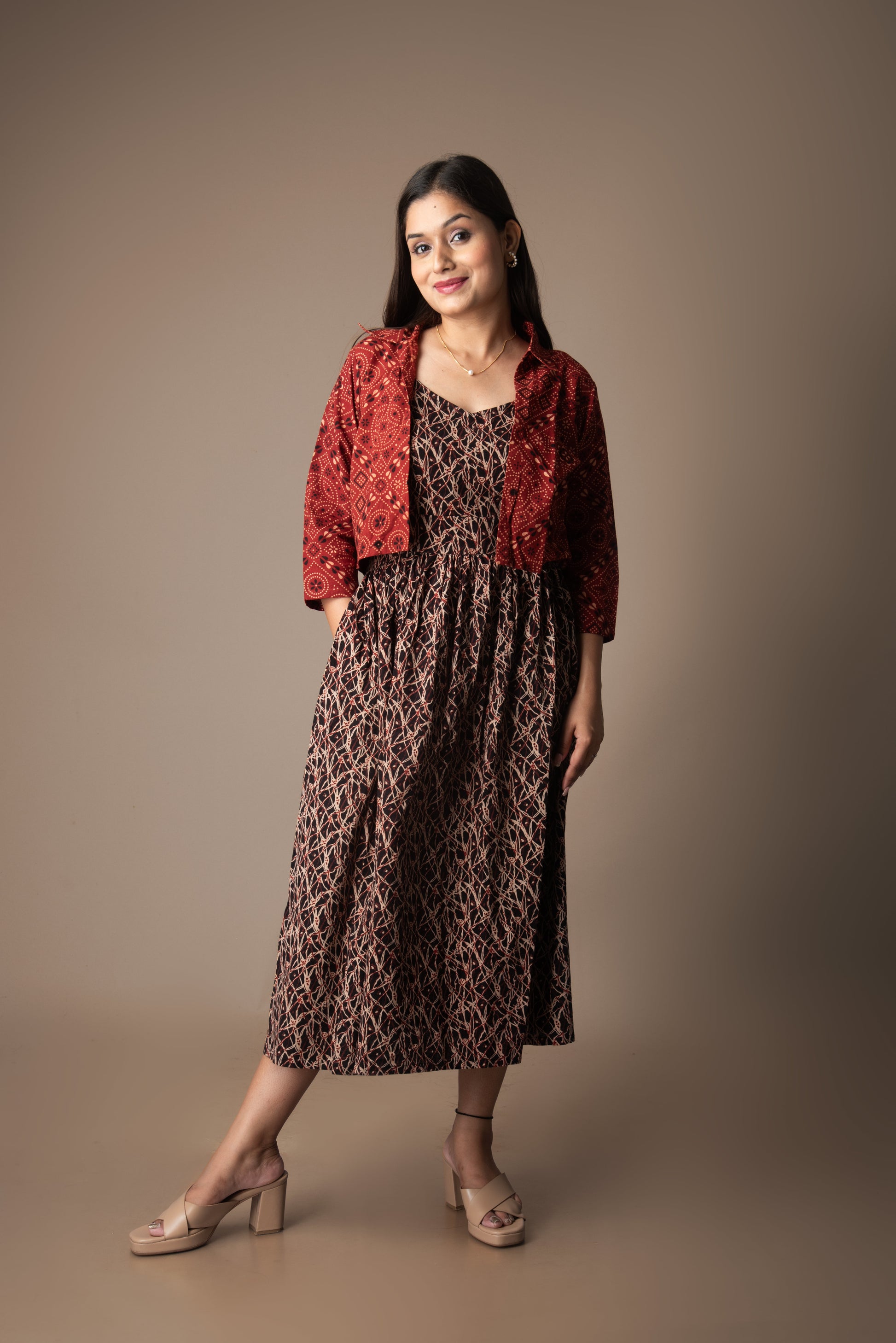 Woman wearing a red patterned jacket over a leopard print dress on a brown background