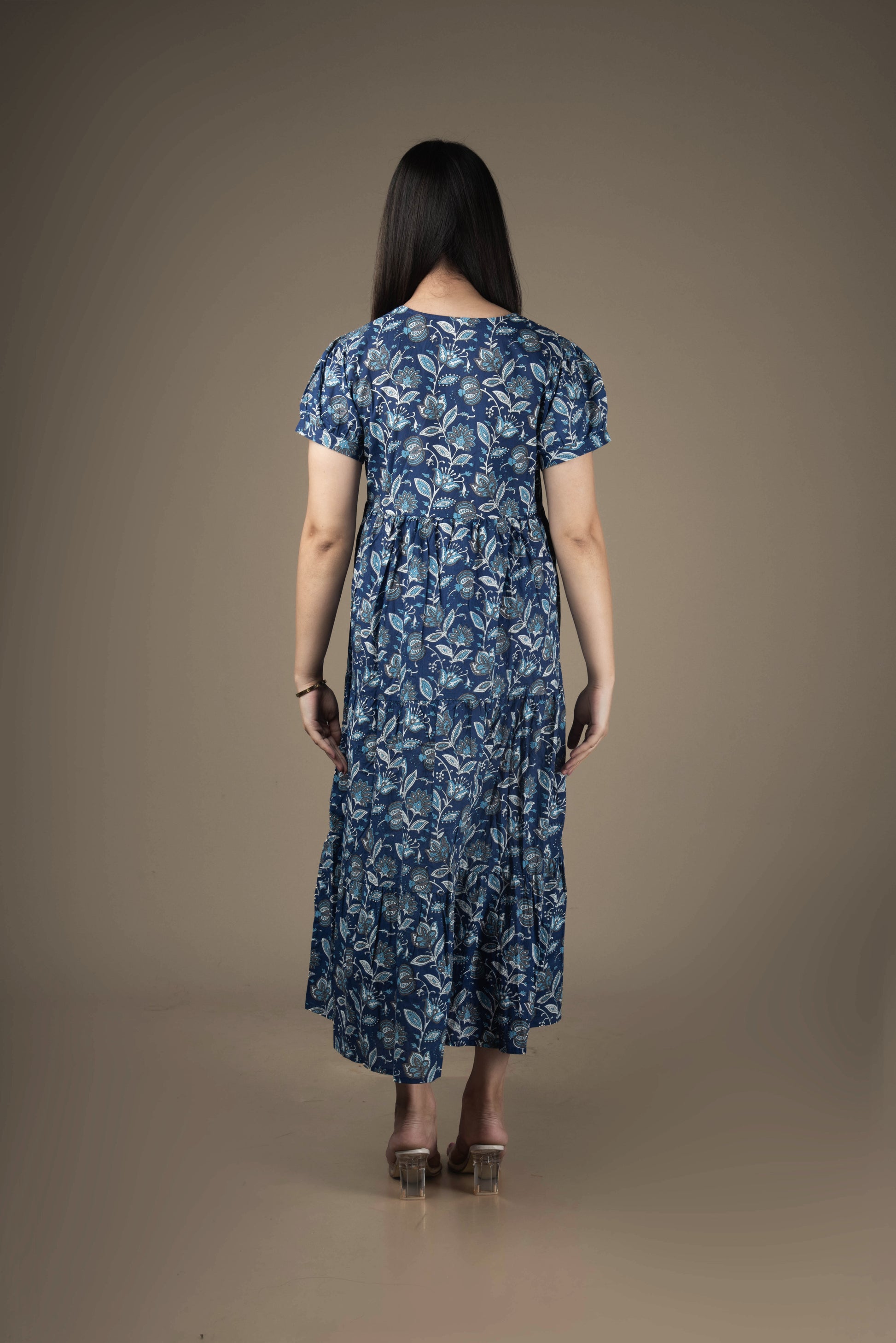 Woman wearing a blue floral dress against a brown background