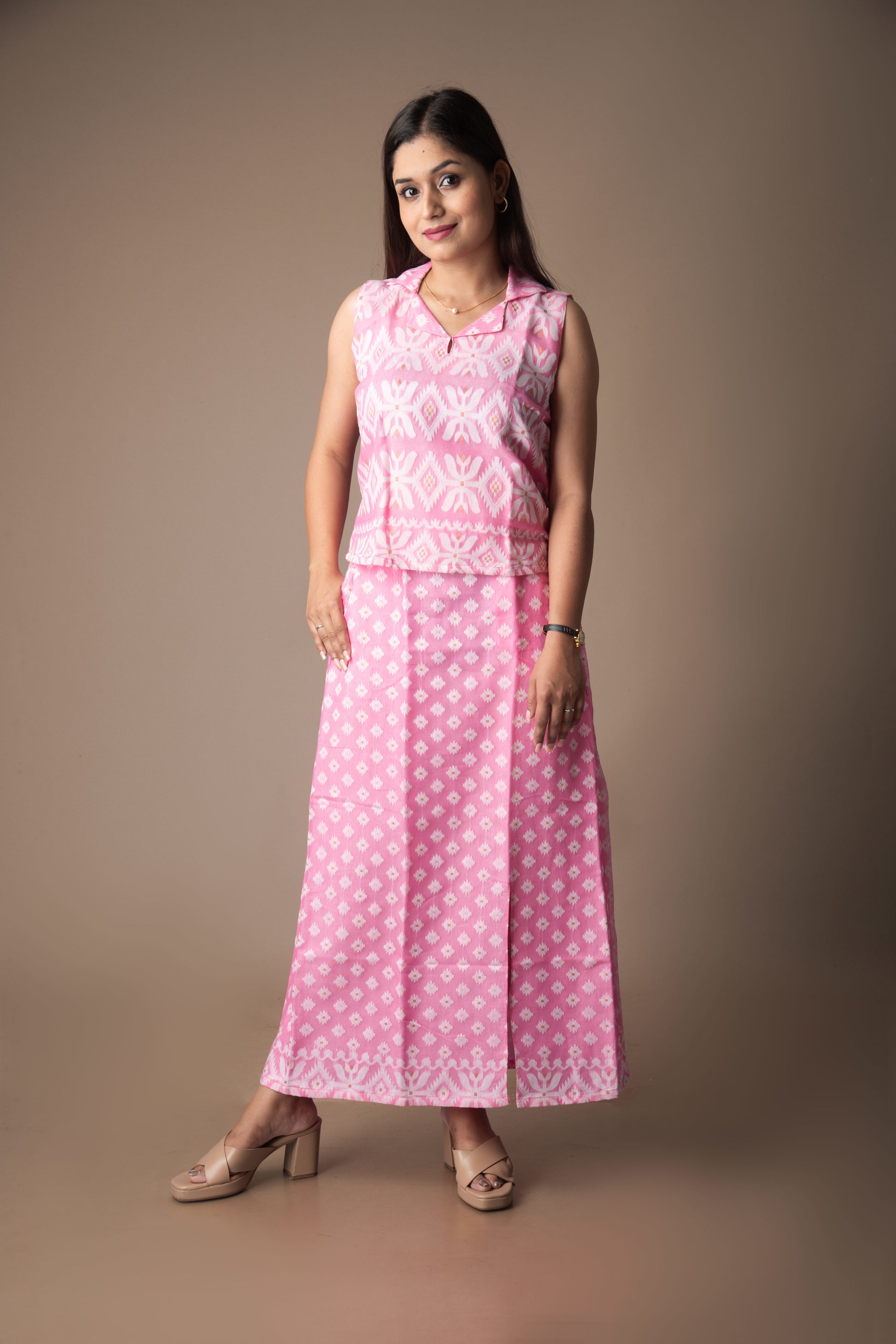 Woman wearing a pink jamdani dress with white patterns against a brown background