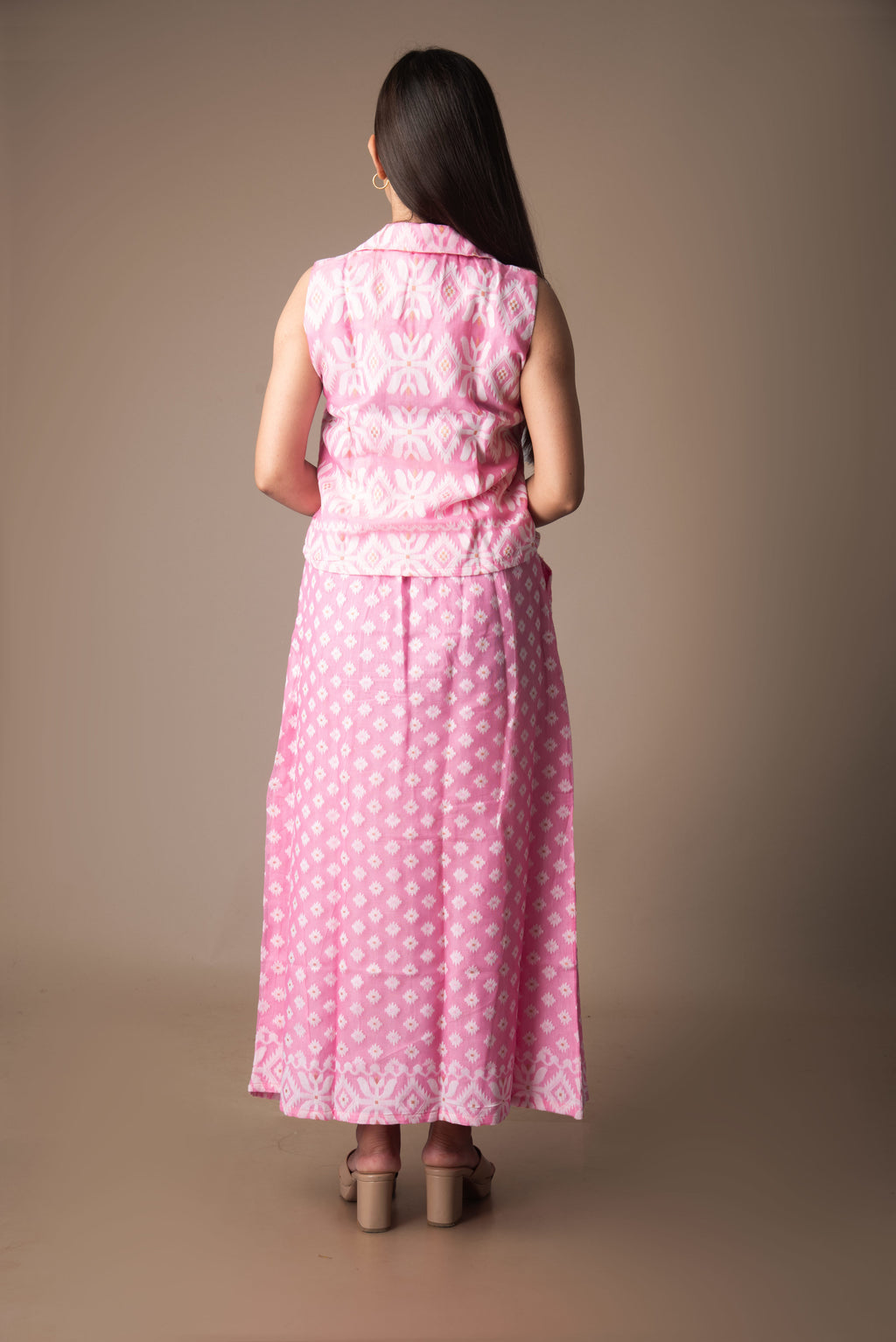 Woman wearing a pink jamdani dress with a subtle pattern on a brown background