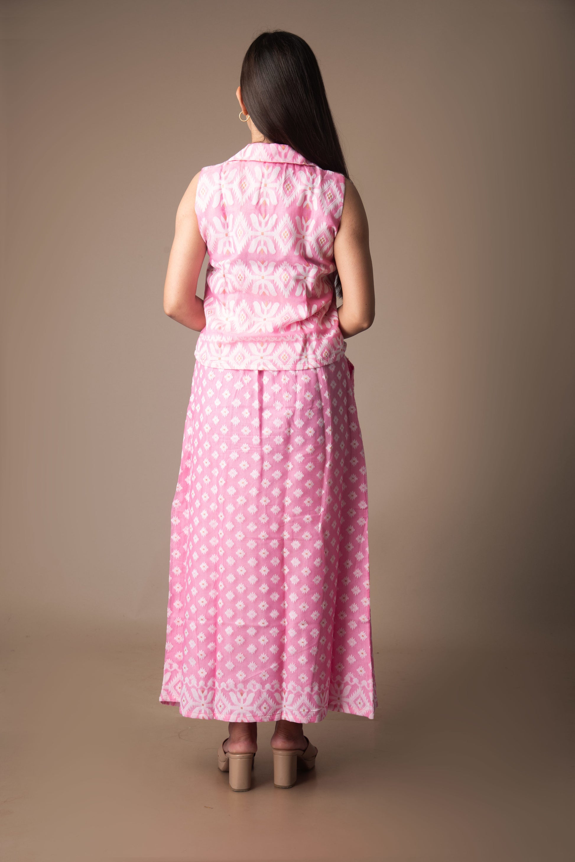 Woman wearing a pink jamdani dress with a subtle pattern on a brown background