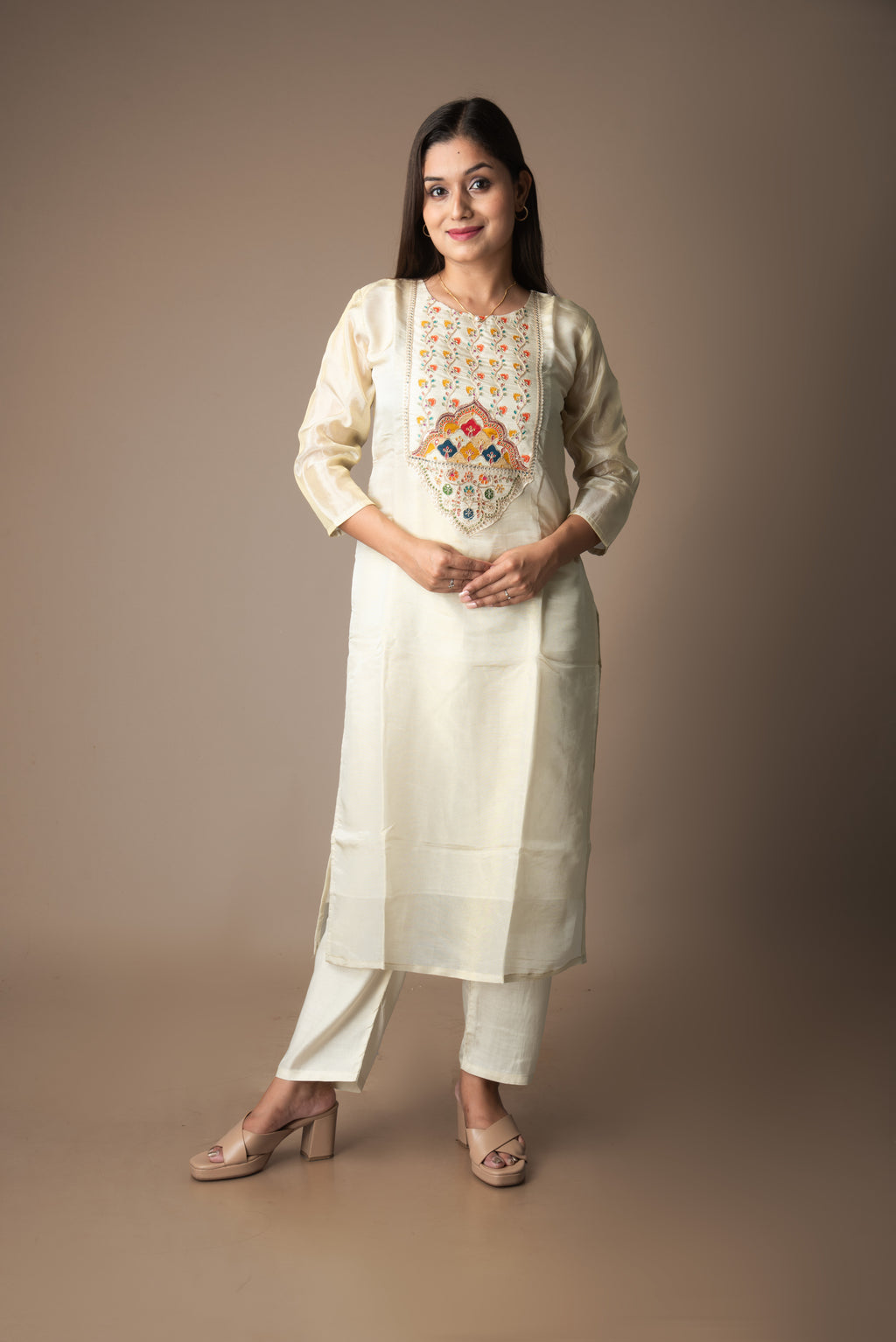 Woman wearing a traditional outfit with an embroidered top on a brown background