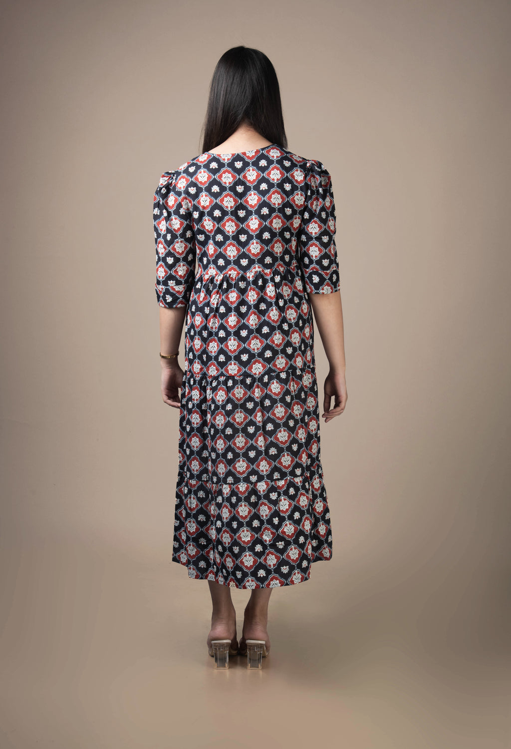 Woman wearing a patterned dress against a beige background
