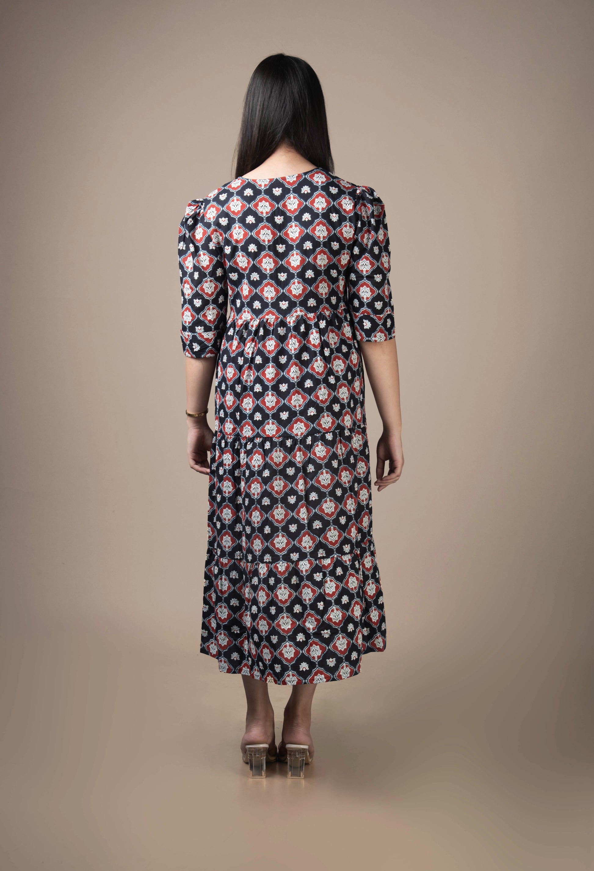 Woman wearing a patterned dress against a beige background