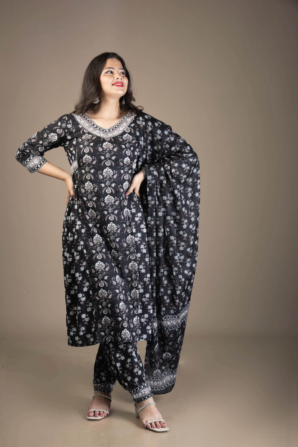 Woman wearing a black floral outfit against a brown background
