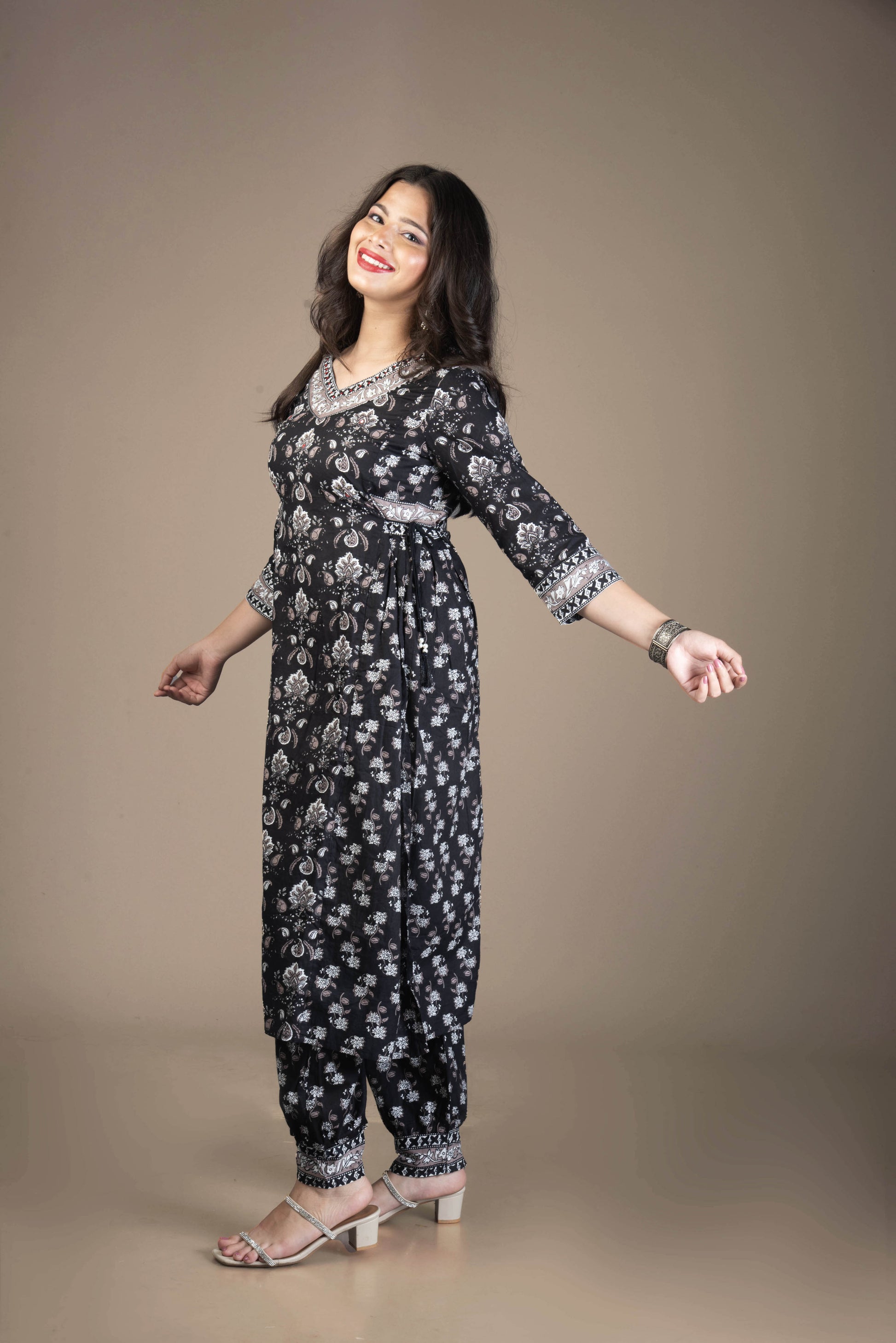 Woman wearing a black floral jumpsuit on a brown background