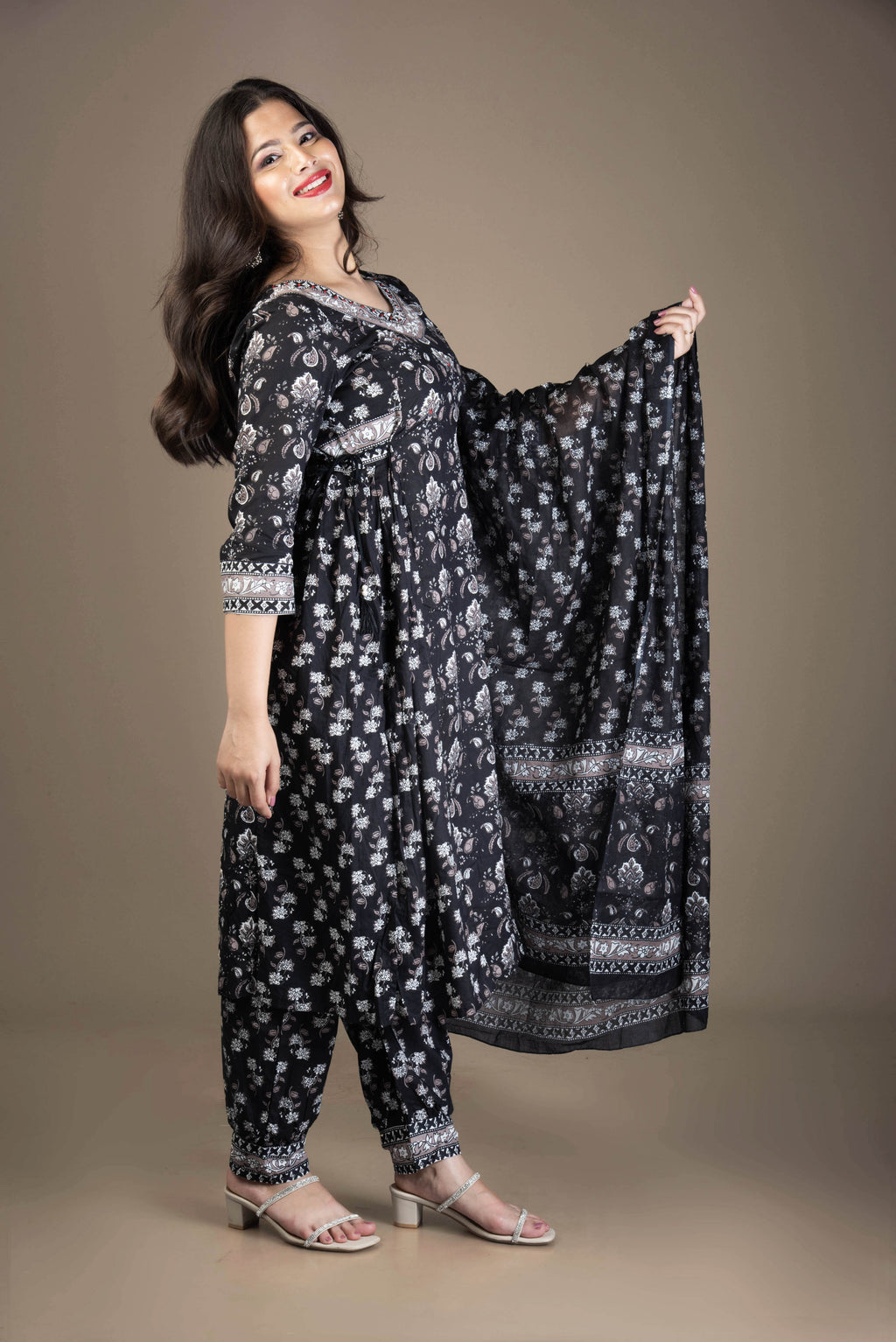 Woman wearing a black and white patterned outfit with a scarf against a brown background