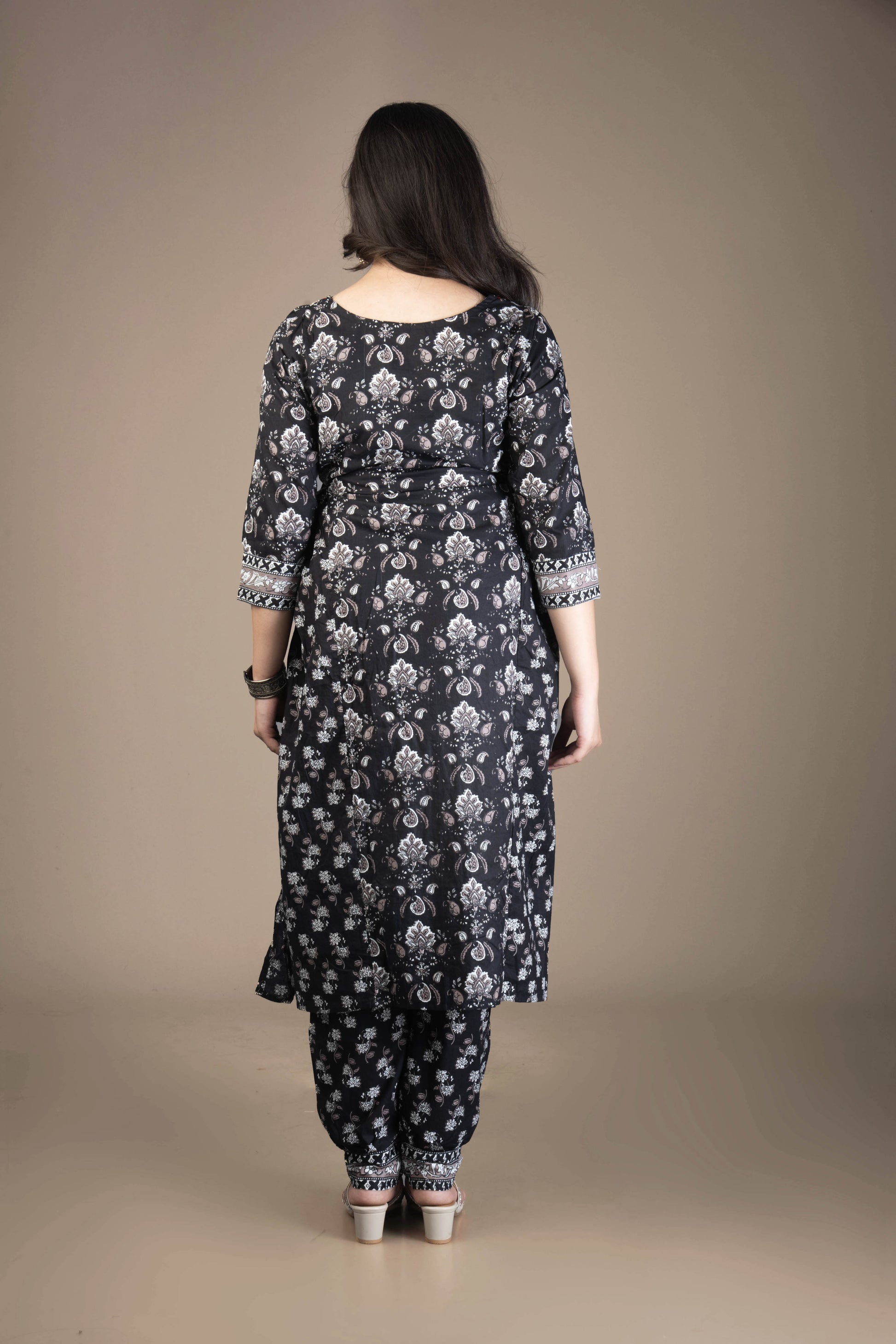 Woman wearing a dark floral patterned outfit against a brown background