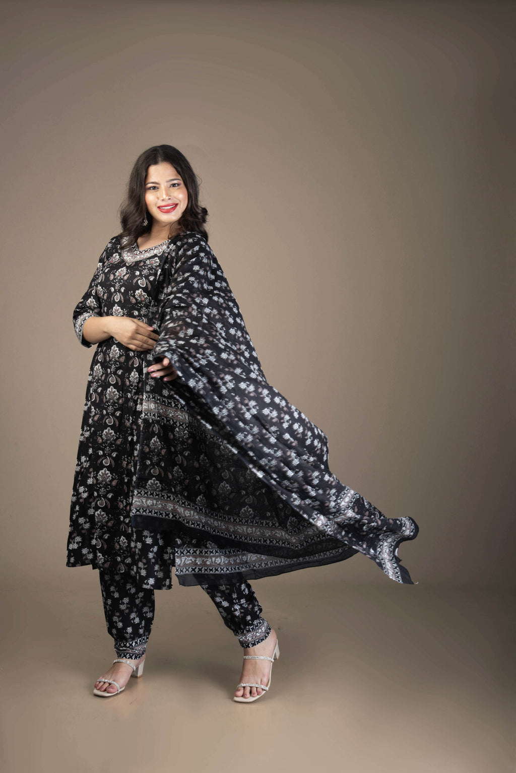 Woman wearing a black floral traditional outfit against a brown background