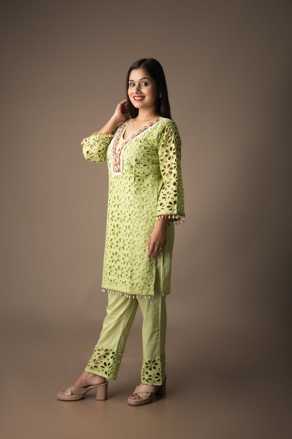 Woman wearing a light green traditional outfit with a plain background