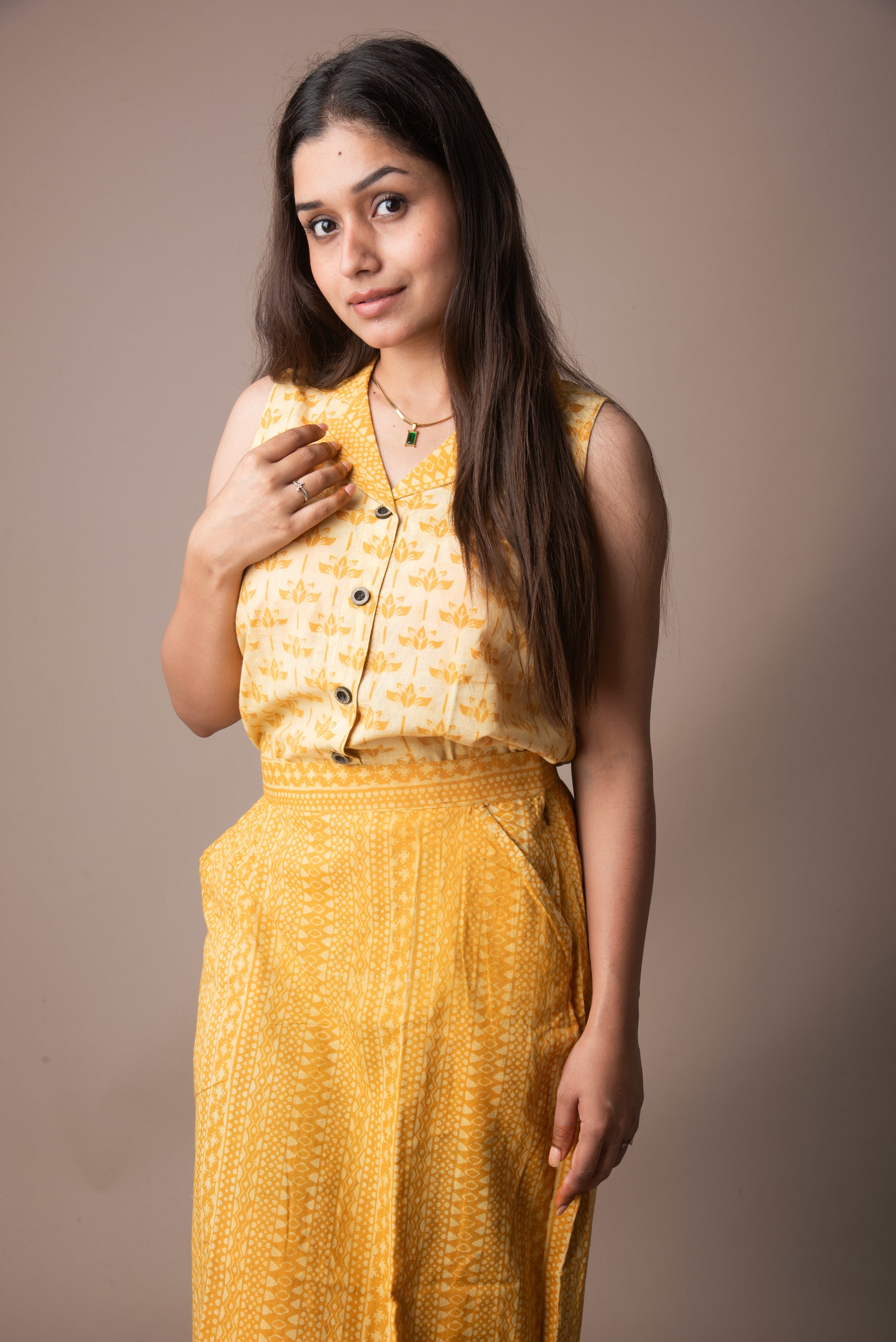Woman wearing a yellow patterned outfit against a brown background