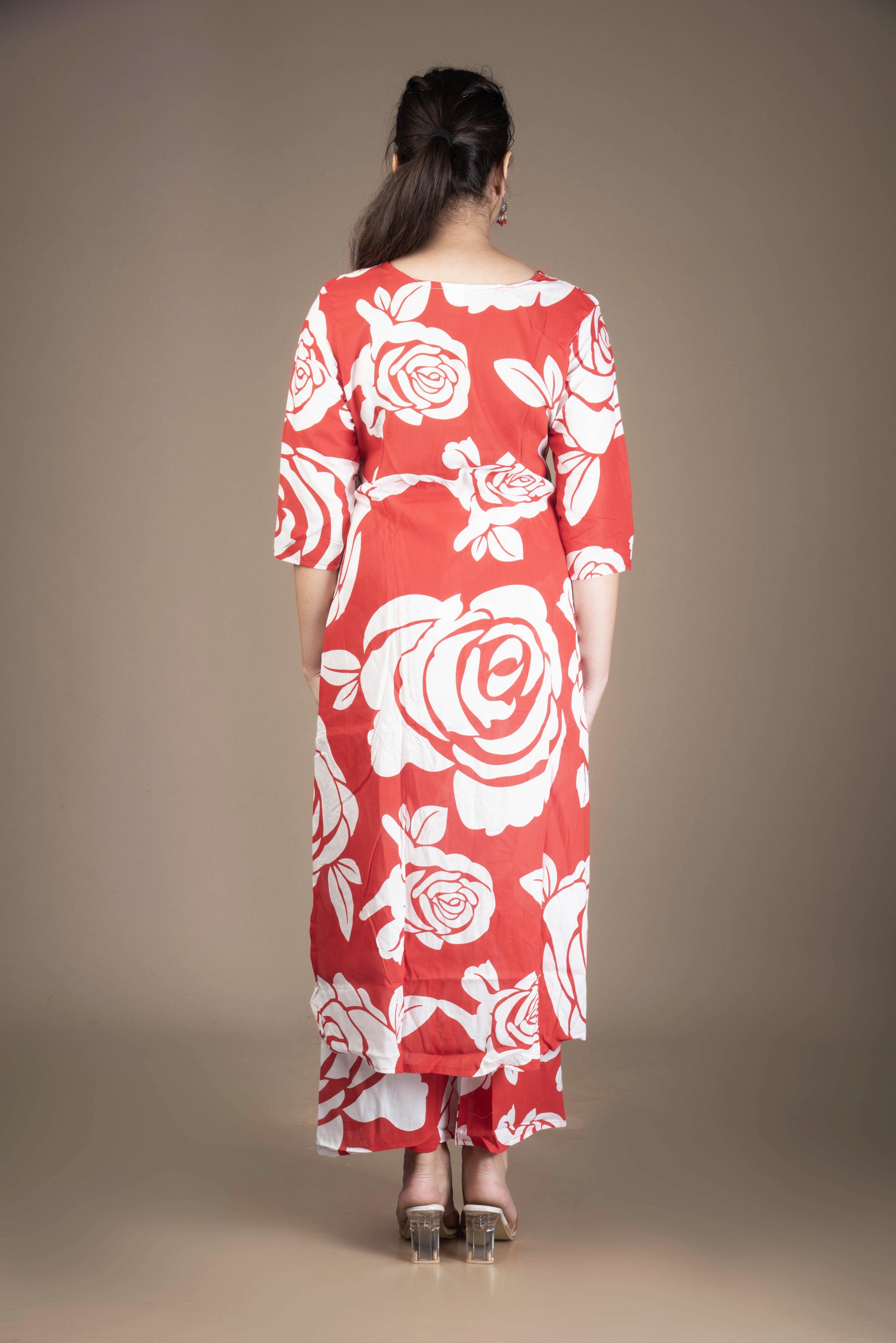 Woman wearing a red dress with white floral patterns against a plain background