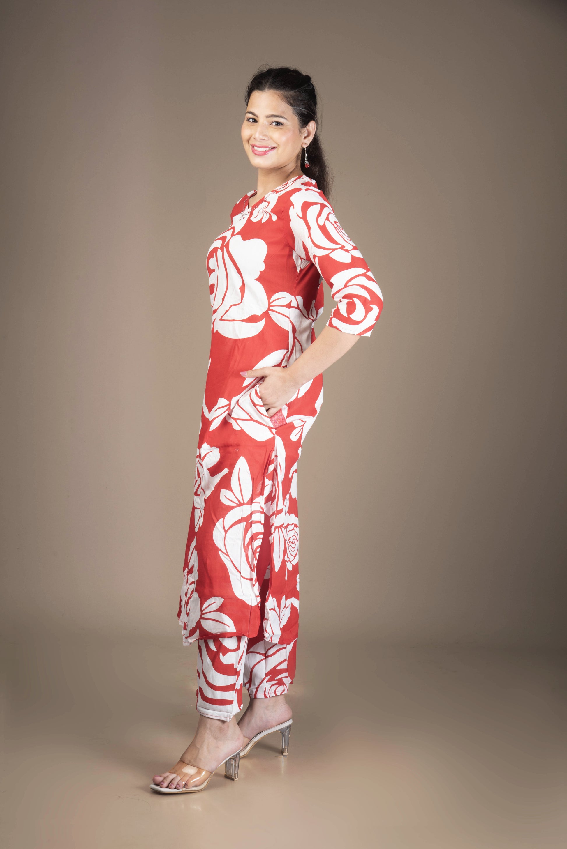 Woman wearing a red and white floral dress against a brown background