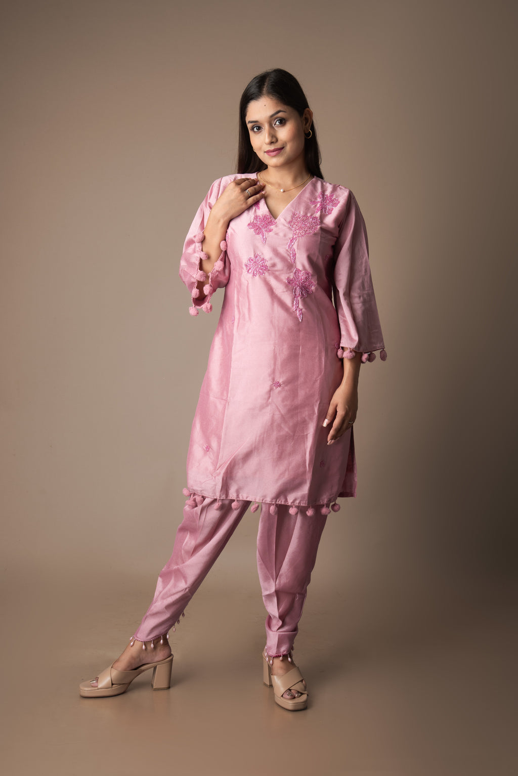 Woman wearing a pink traditional outfit with floral patterns on a brown background
