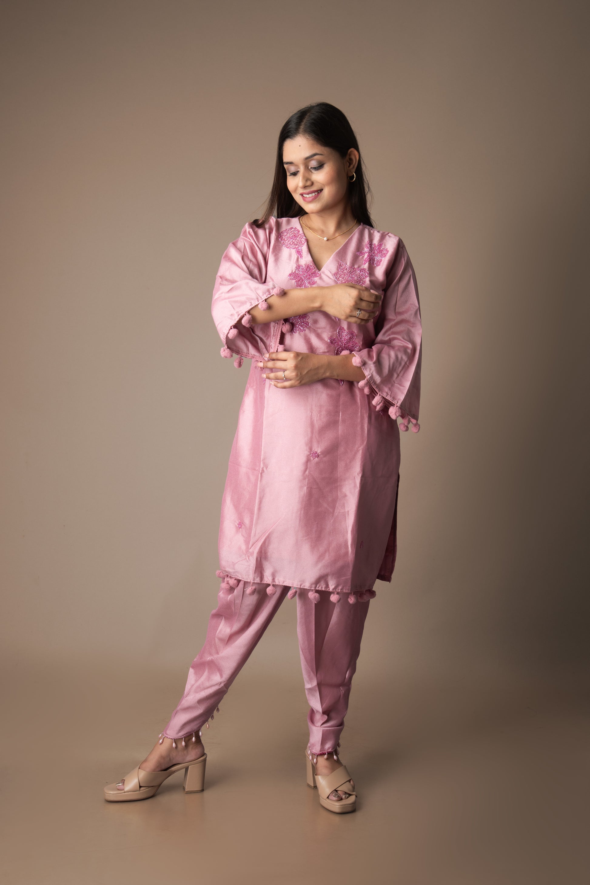Woman wearing a pink satin outfit against a brown background