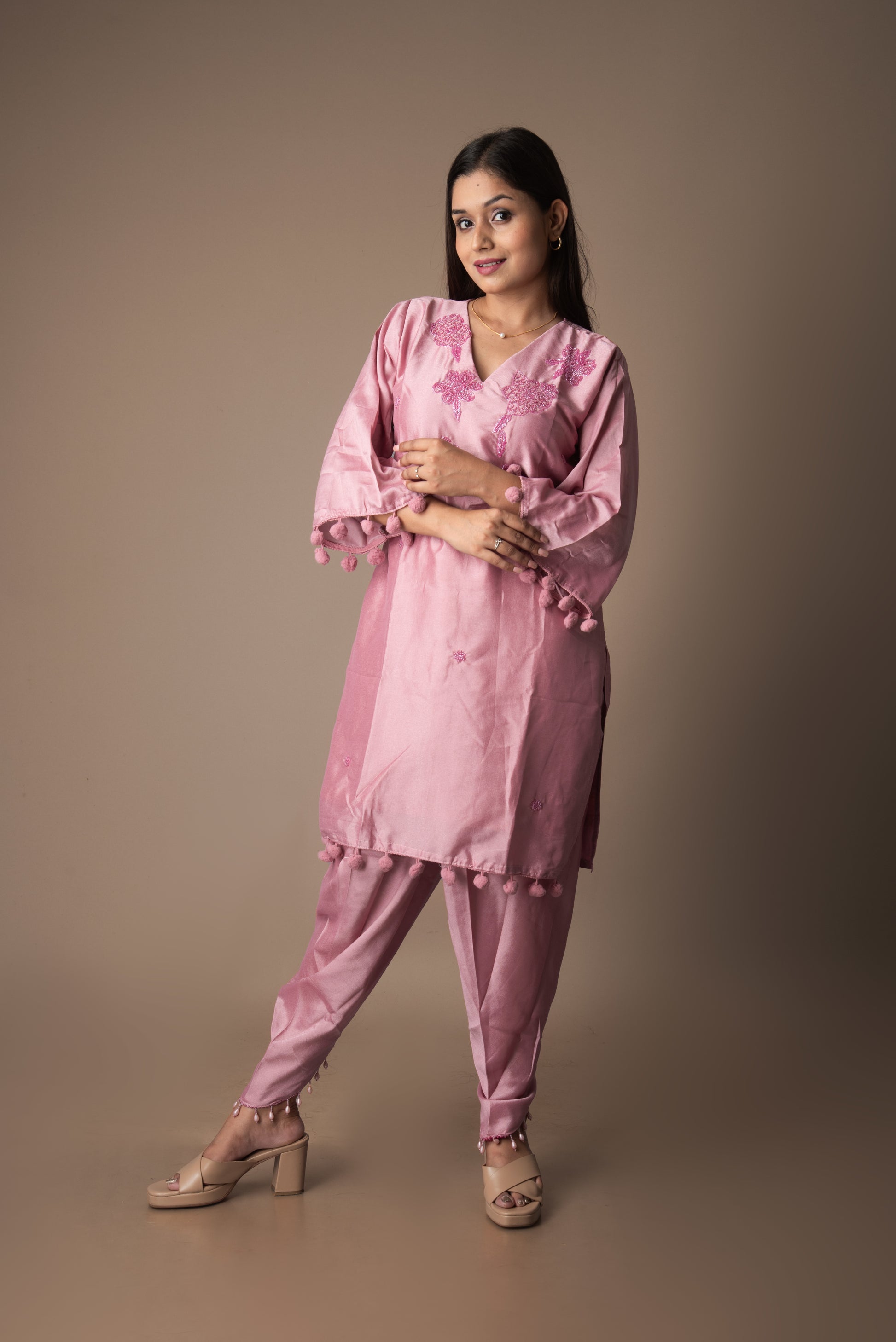 Woman wearing a pink traditional outfit against a brown background