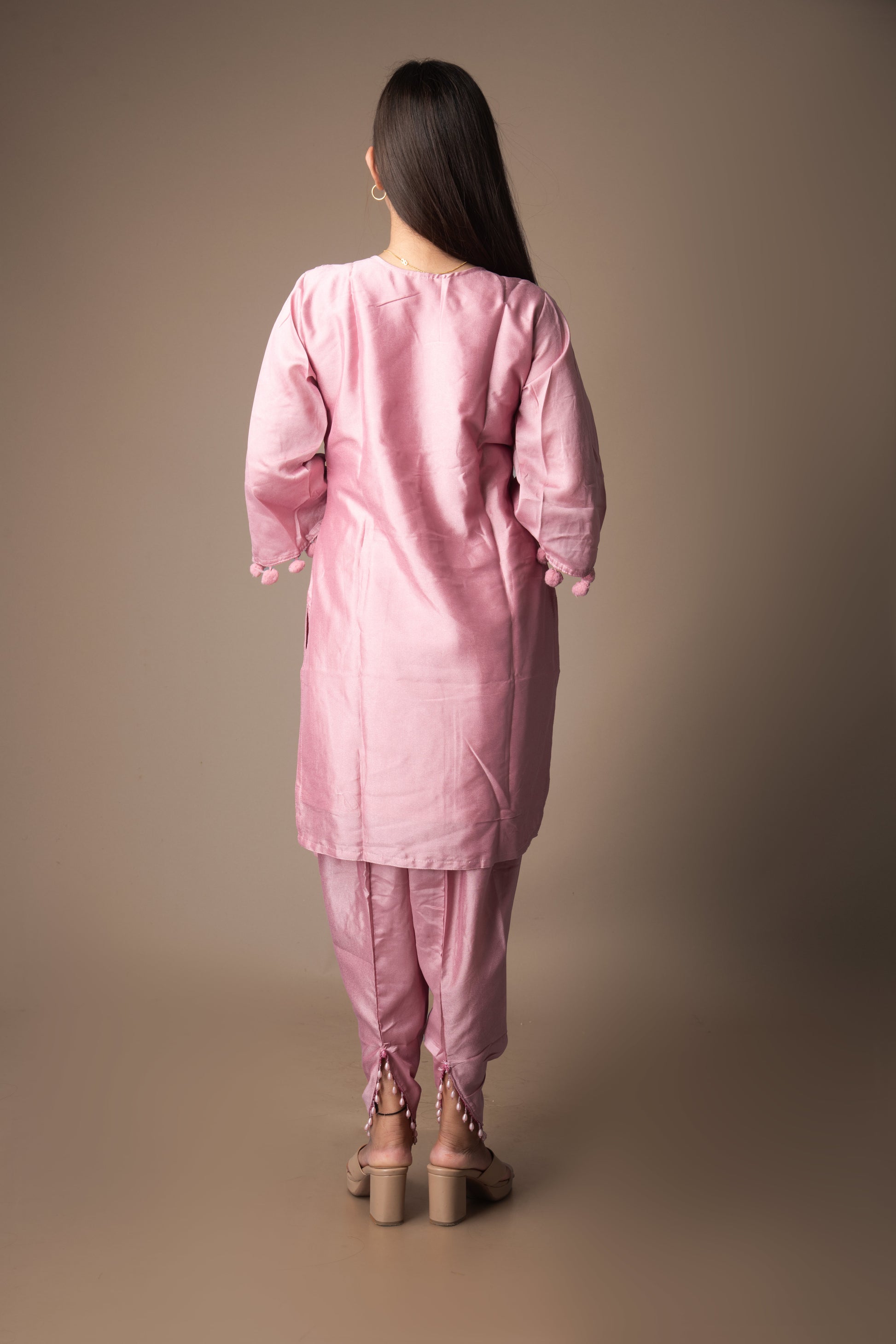 Woman wearing a pink traditional outfit against a brown background