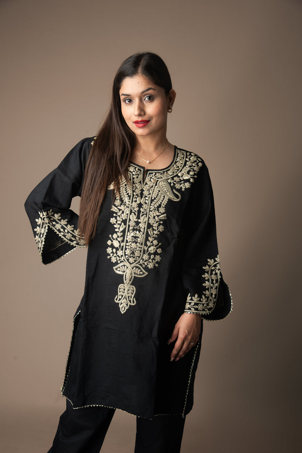 Woman wearing a black embroidered top against a brown background