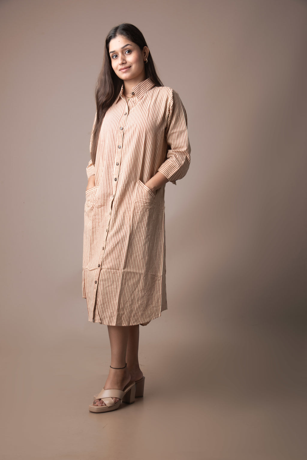 Woman wearing a beige checkered dress against a brown background