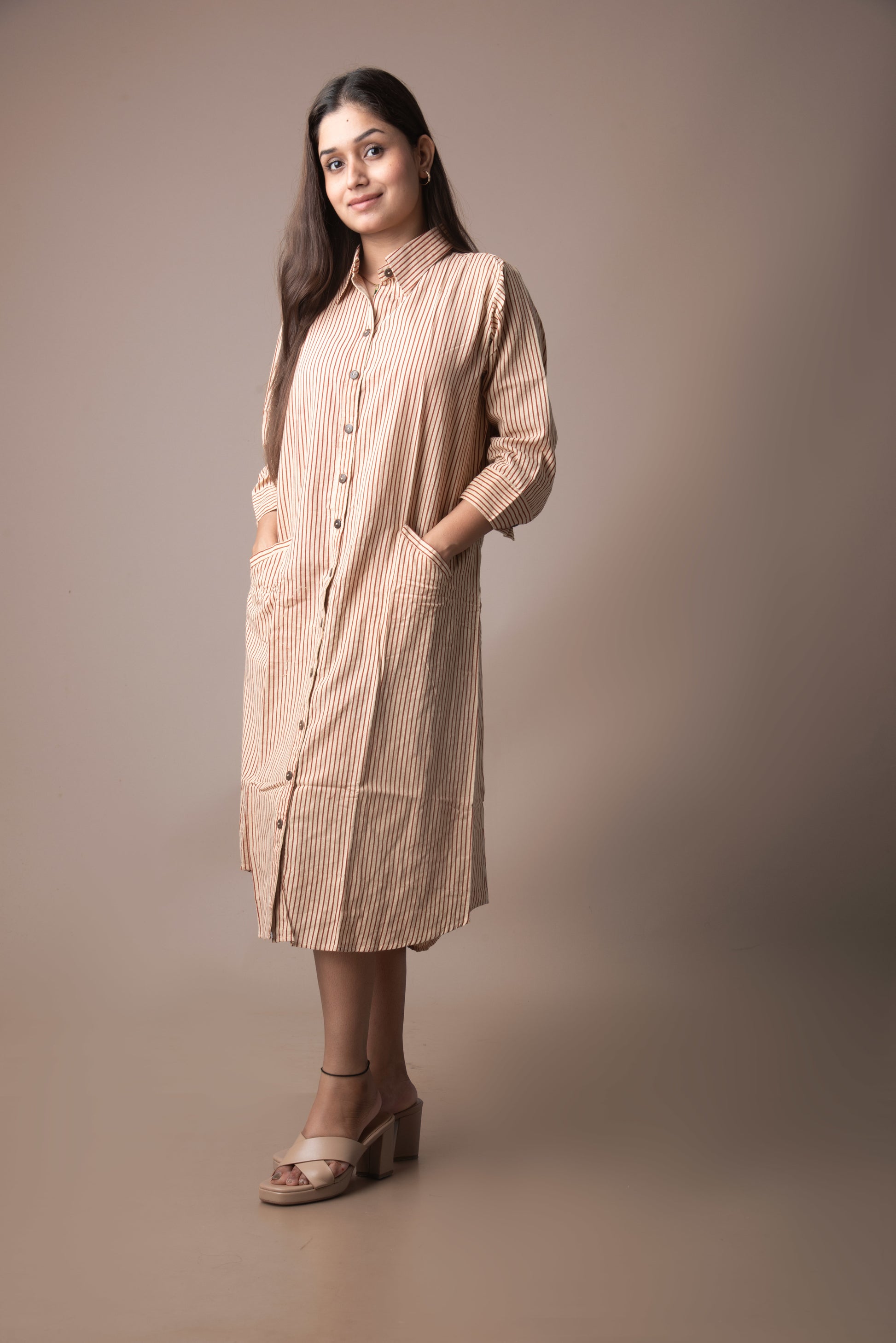 Woman wearing a beige checkered dress against a brown background