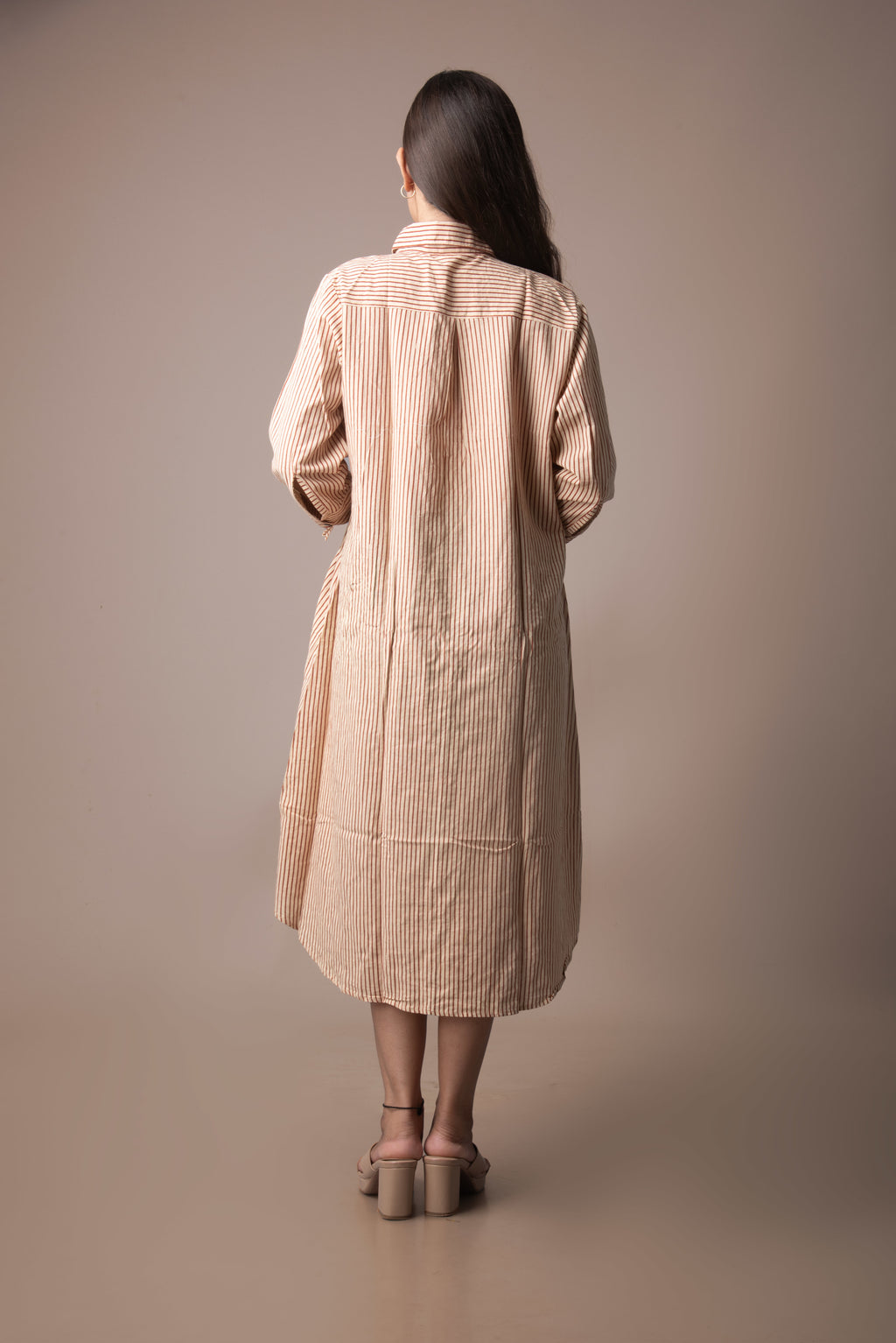 Woman wearing a beige trench coat against a plain background