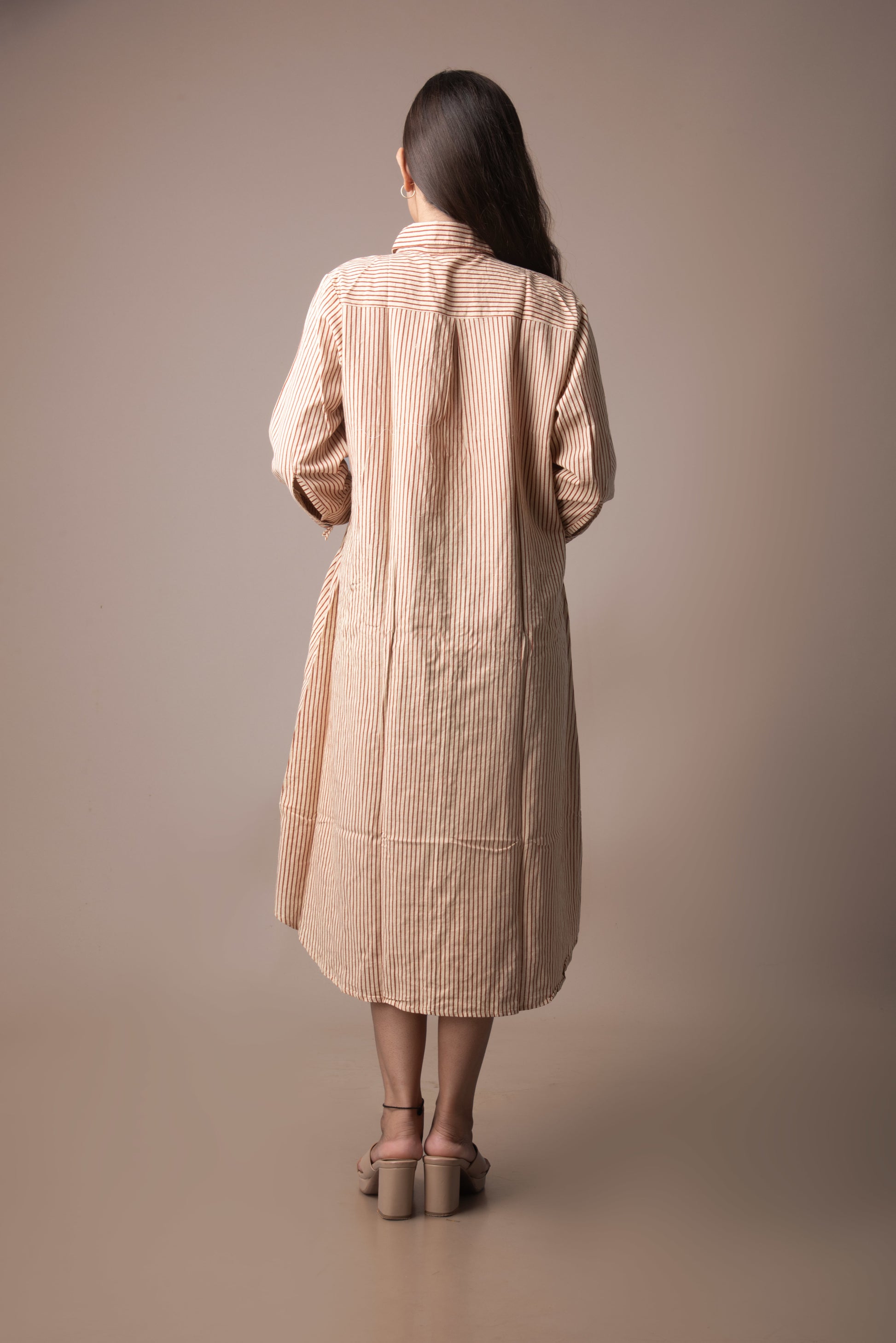 Woman wearing a beige trench coat against a plain background