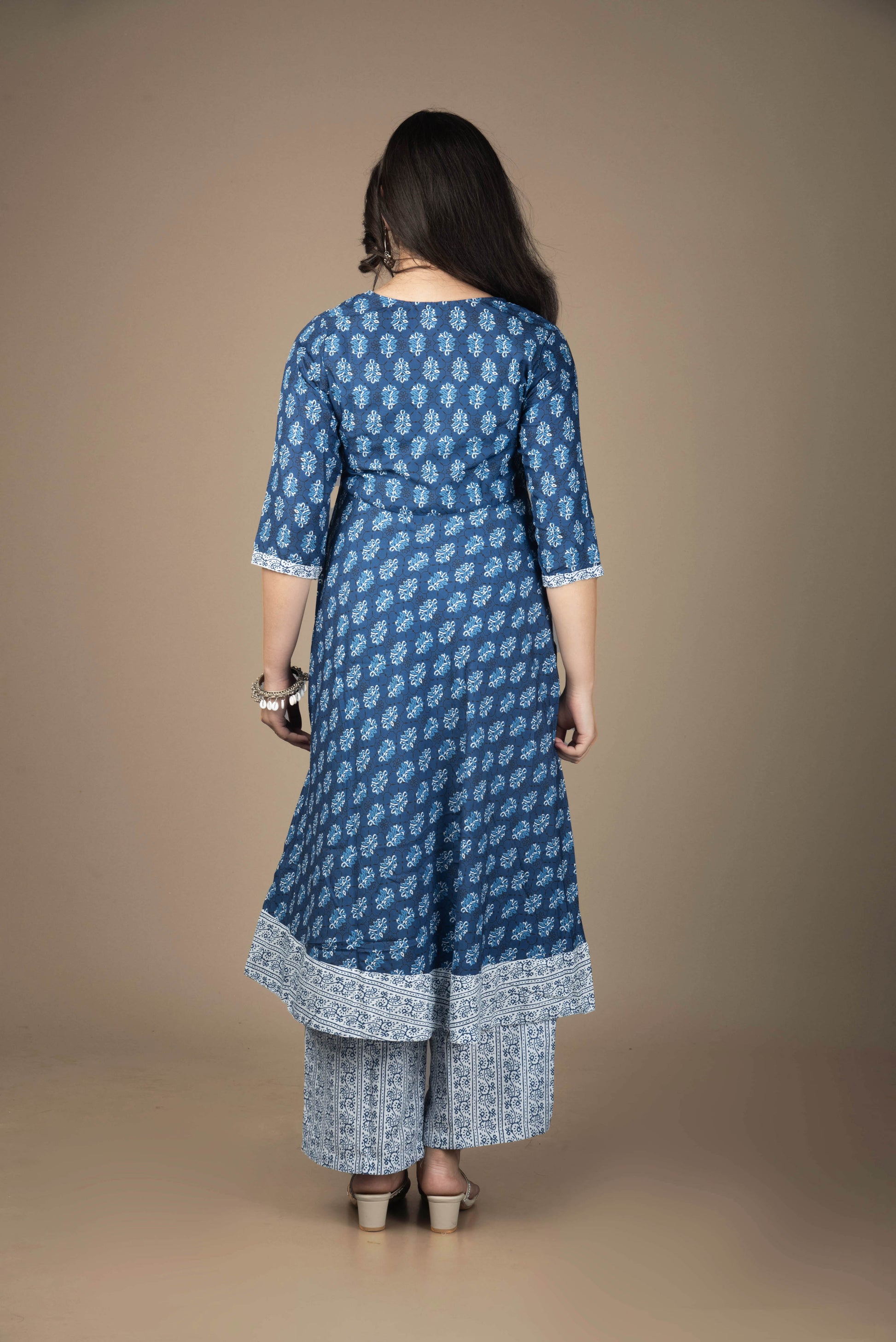 Woman wearing a blue patterned kurta with pants against a brown background