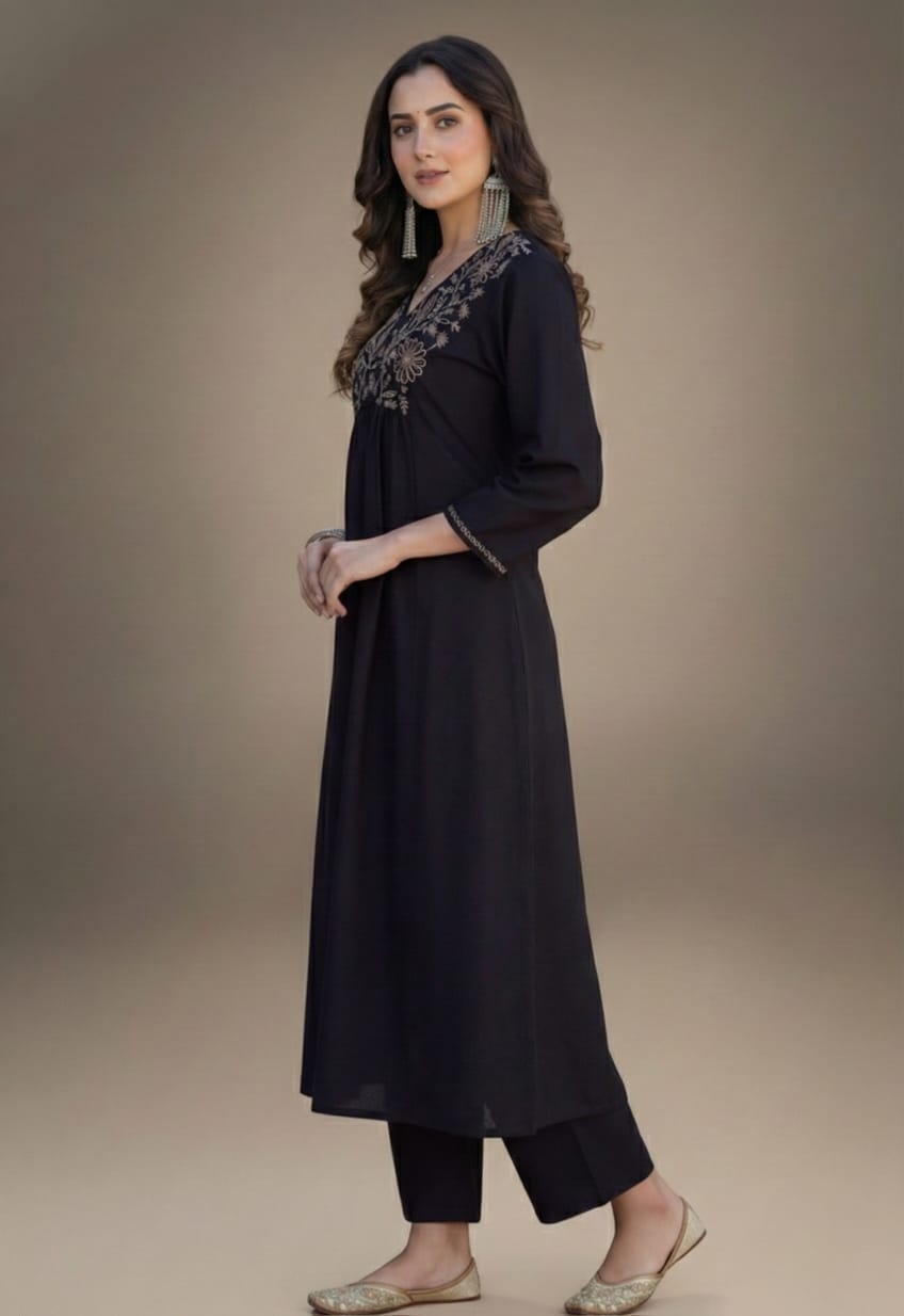 Woman wearing a black outfit with intricate detailing on a beige background