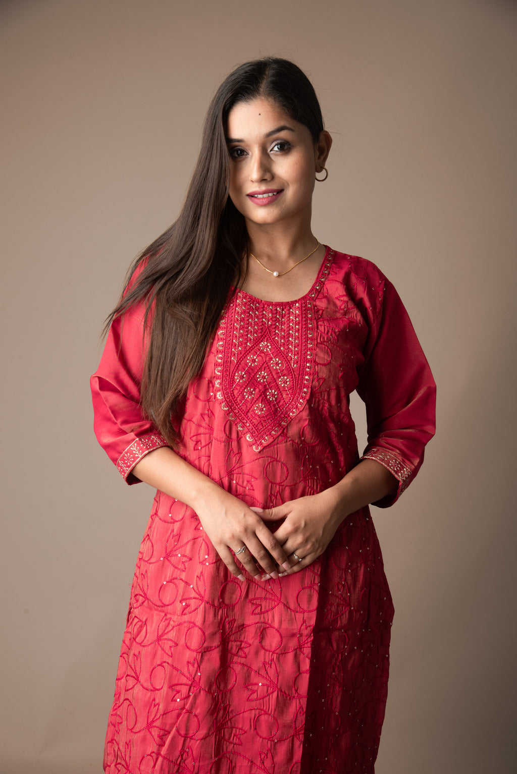 Woman wearing a red embroidered dress against a brown background