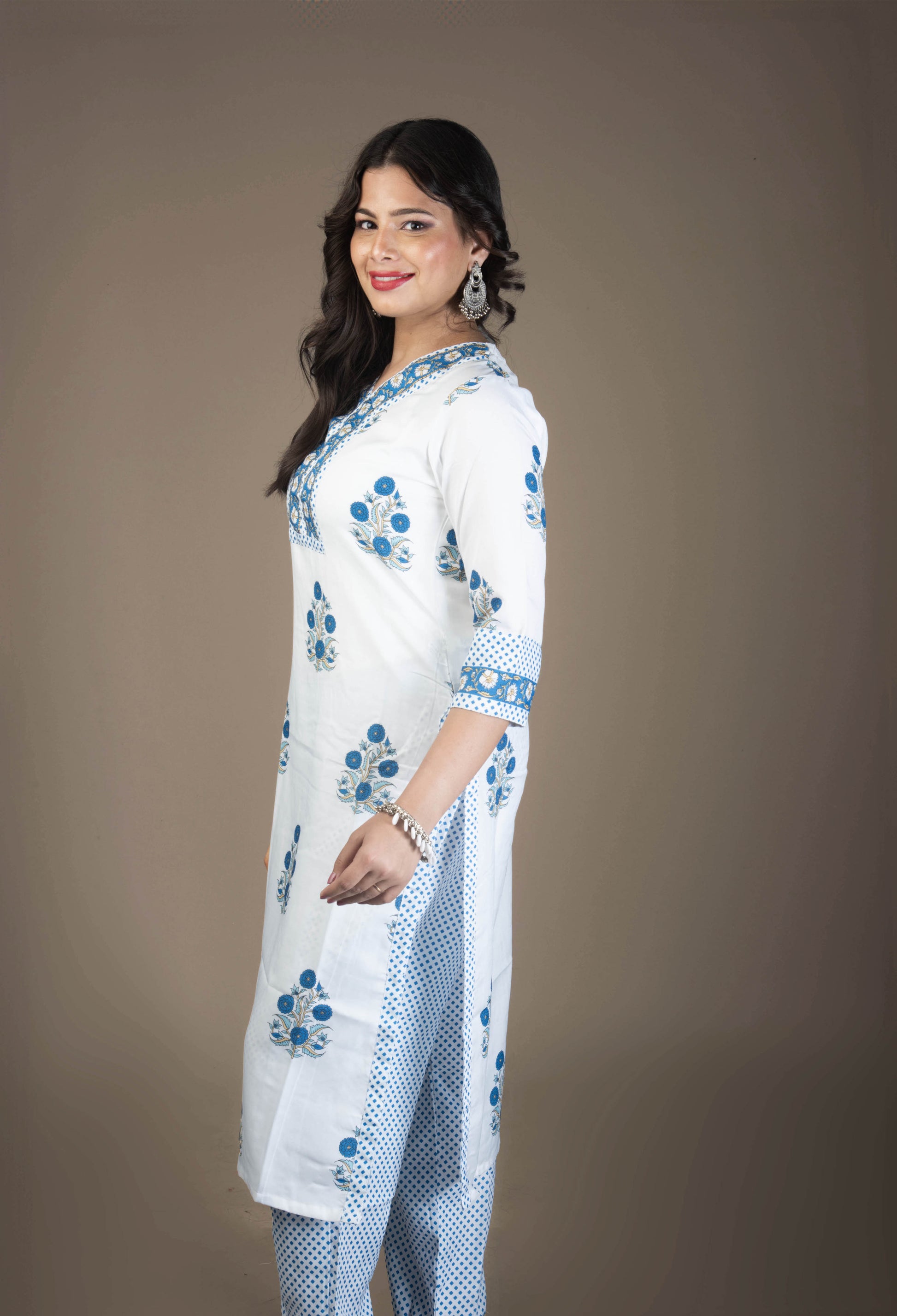 Woman wearing a white traditional outfit with blue patterns on a brown background