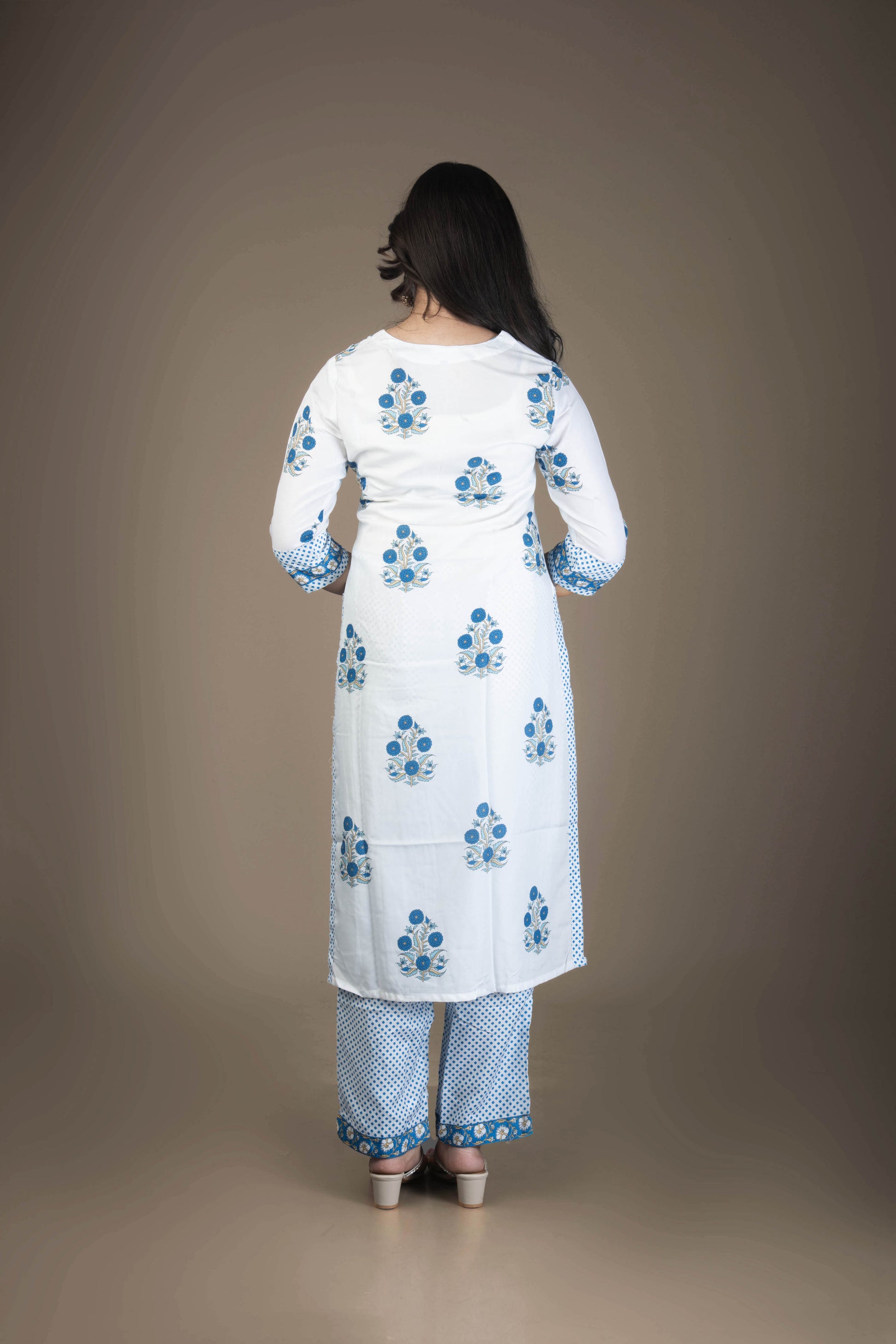 Woman wearing a white kurta with blue floral patterns on a plain background