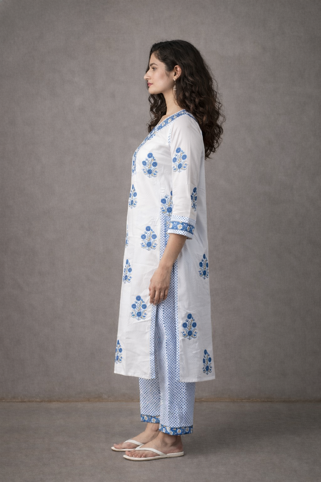 Woman wearing a white kurta with blue floral patterns against a gray background