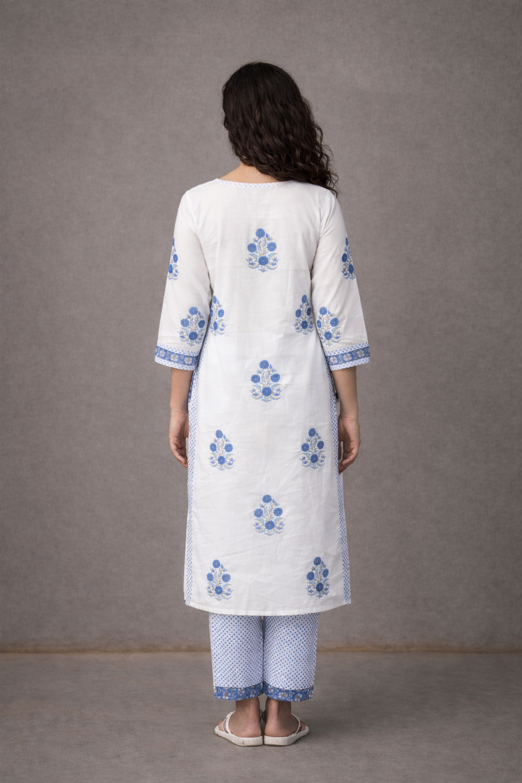 Woman wearing a white kurta with blue floral patterns on a gray background