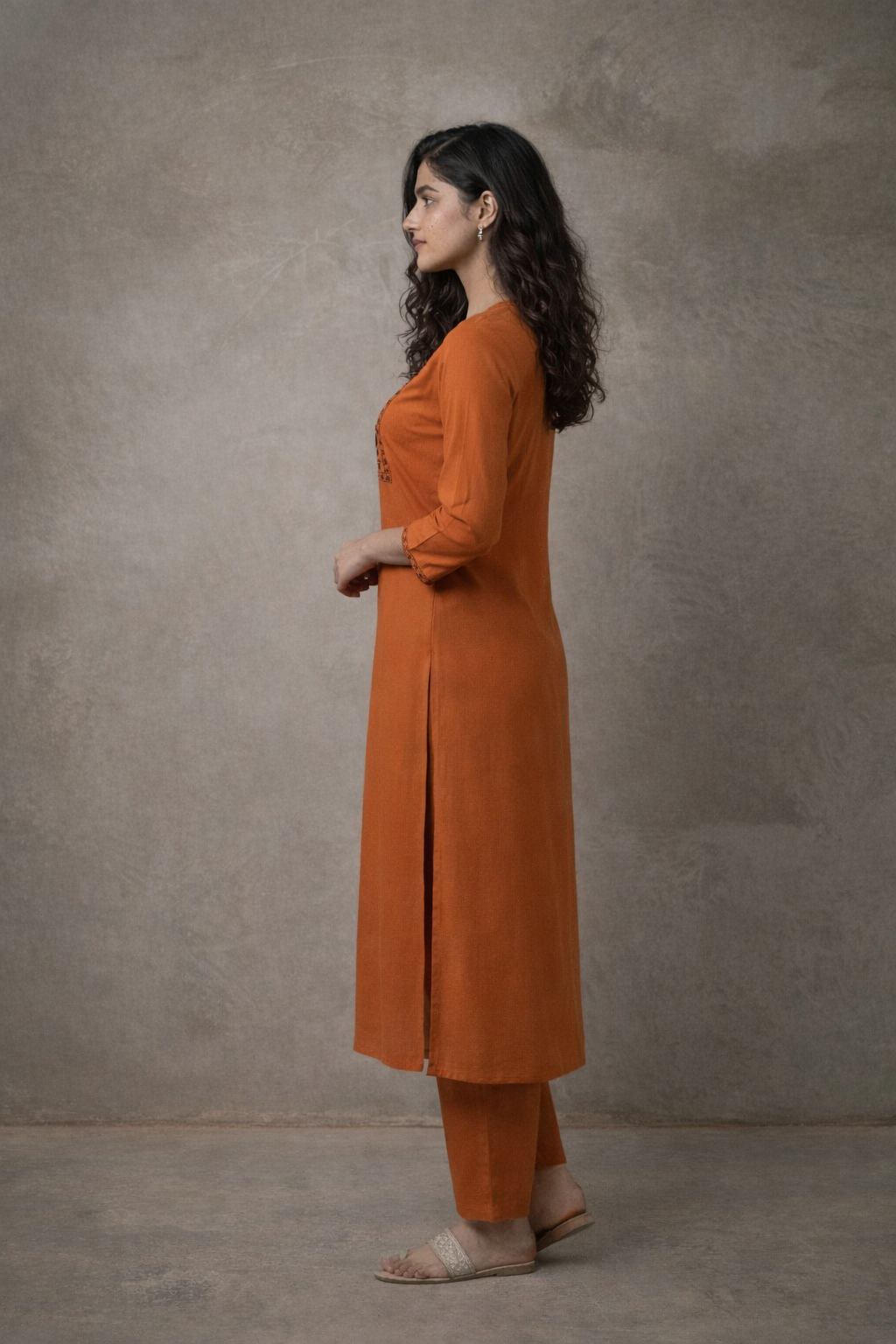 Woman wearing an orange kurta with a plain background