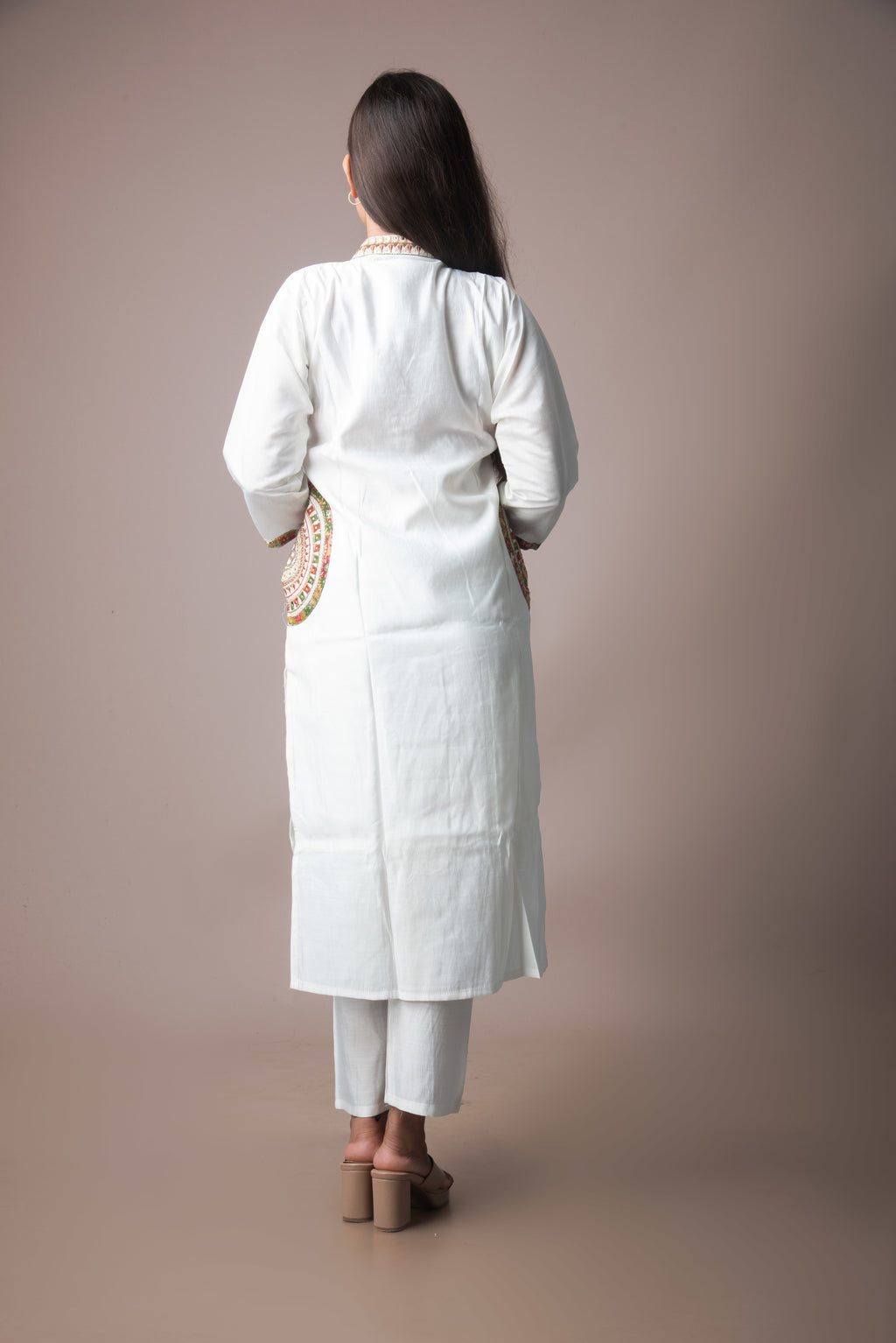 Woman wearing a white traditional outfit against a plain background