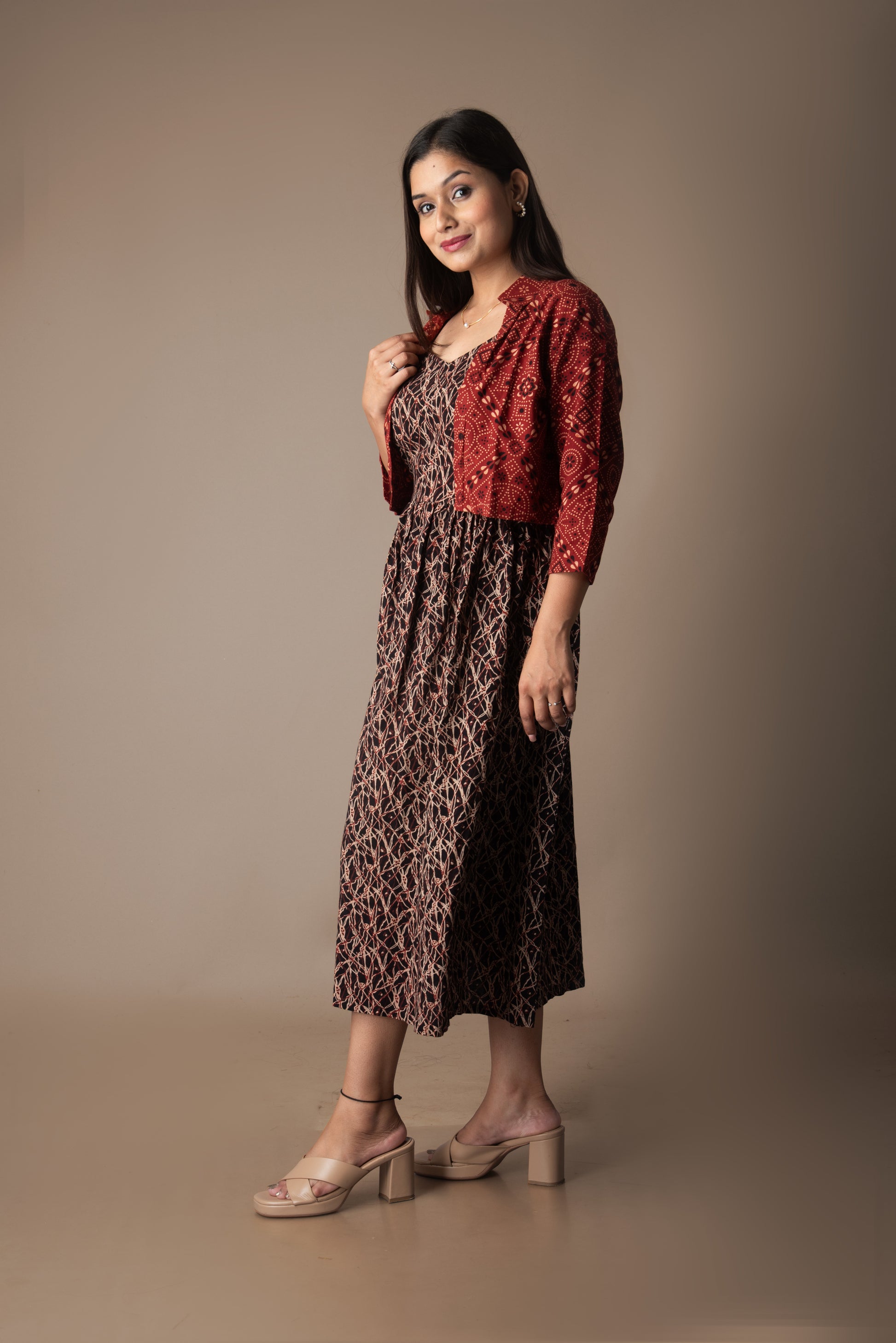 Woman wearing a patterned dress and red shawl against a brown background