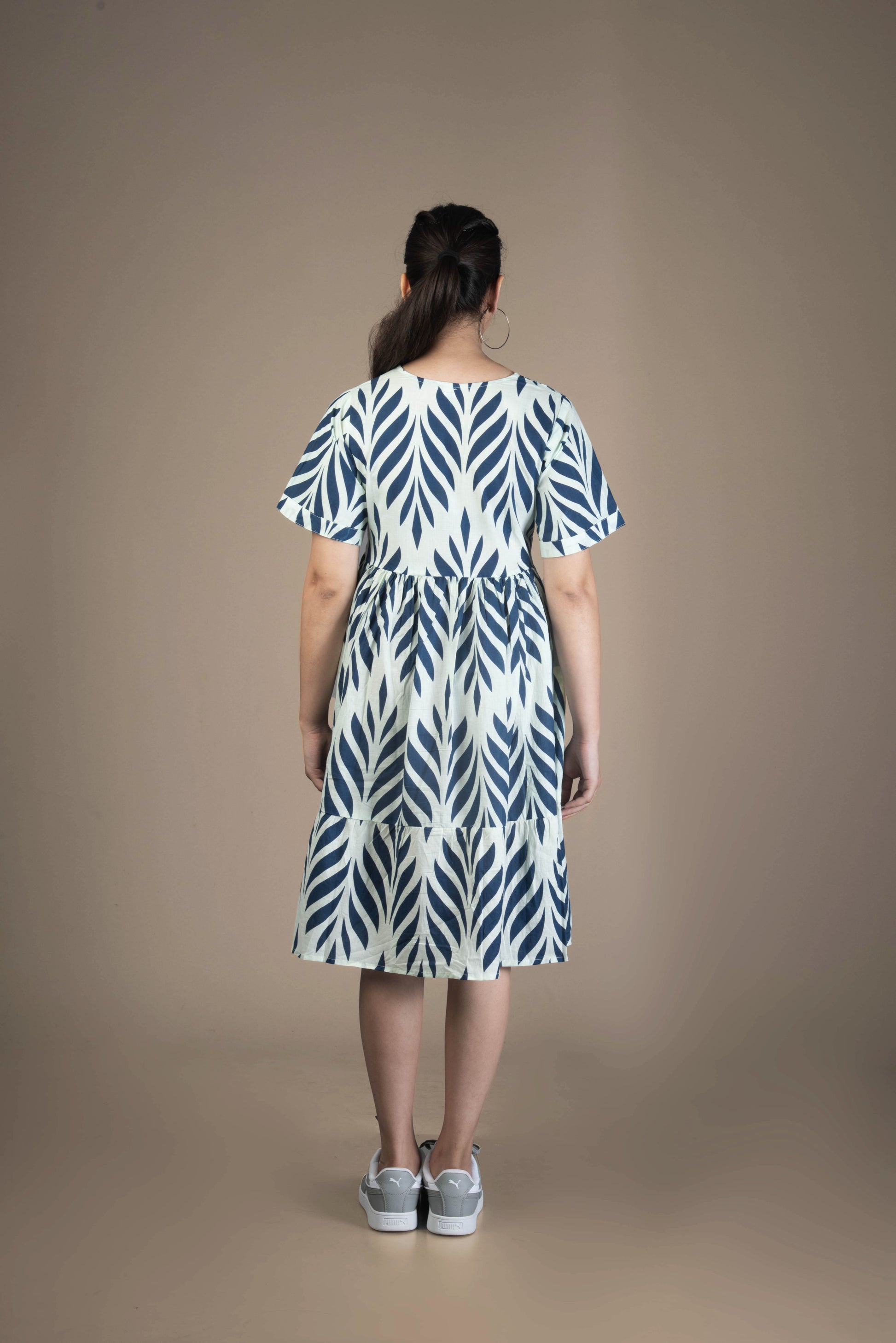 Woman wearing a blue and white patterned dress on a brown background