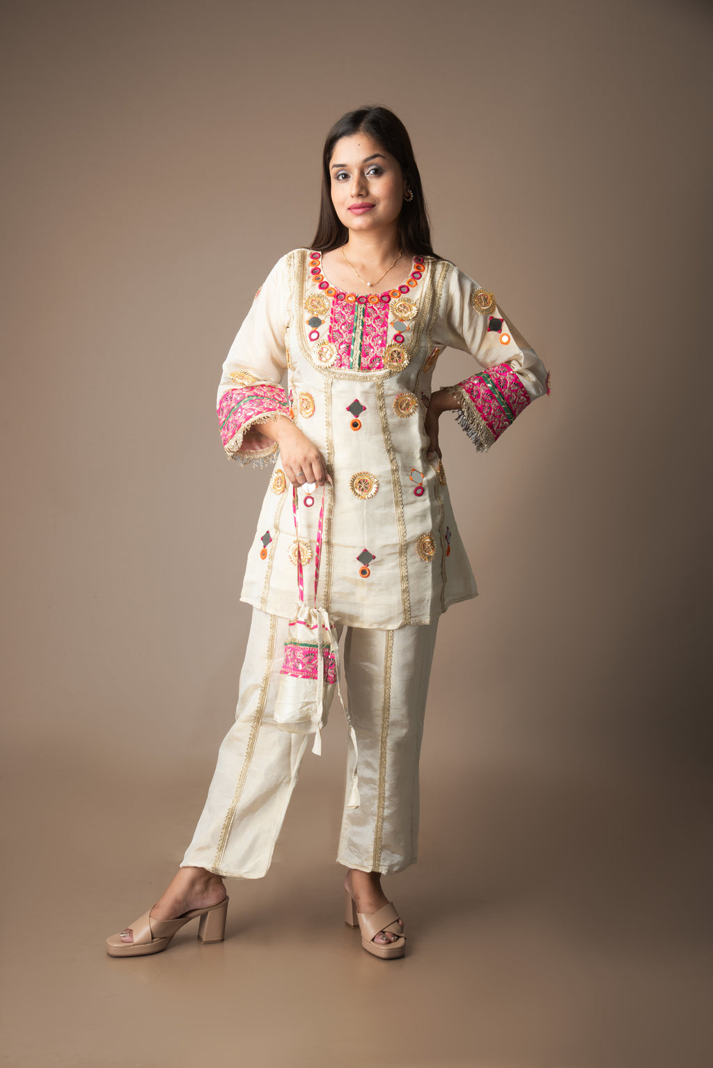 Woman wearing a traditional embroidered outfit with a plain background