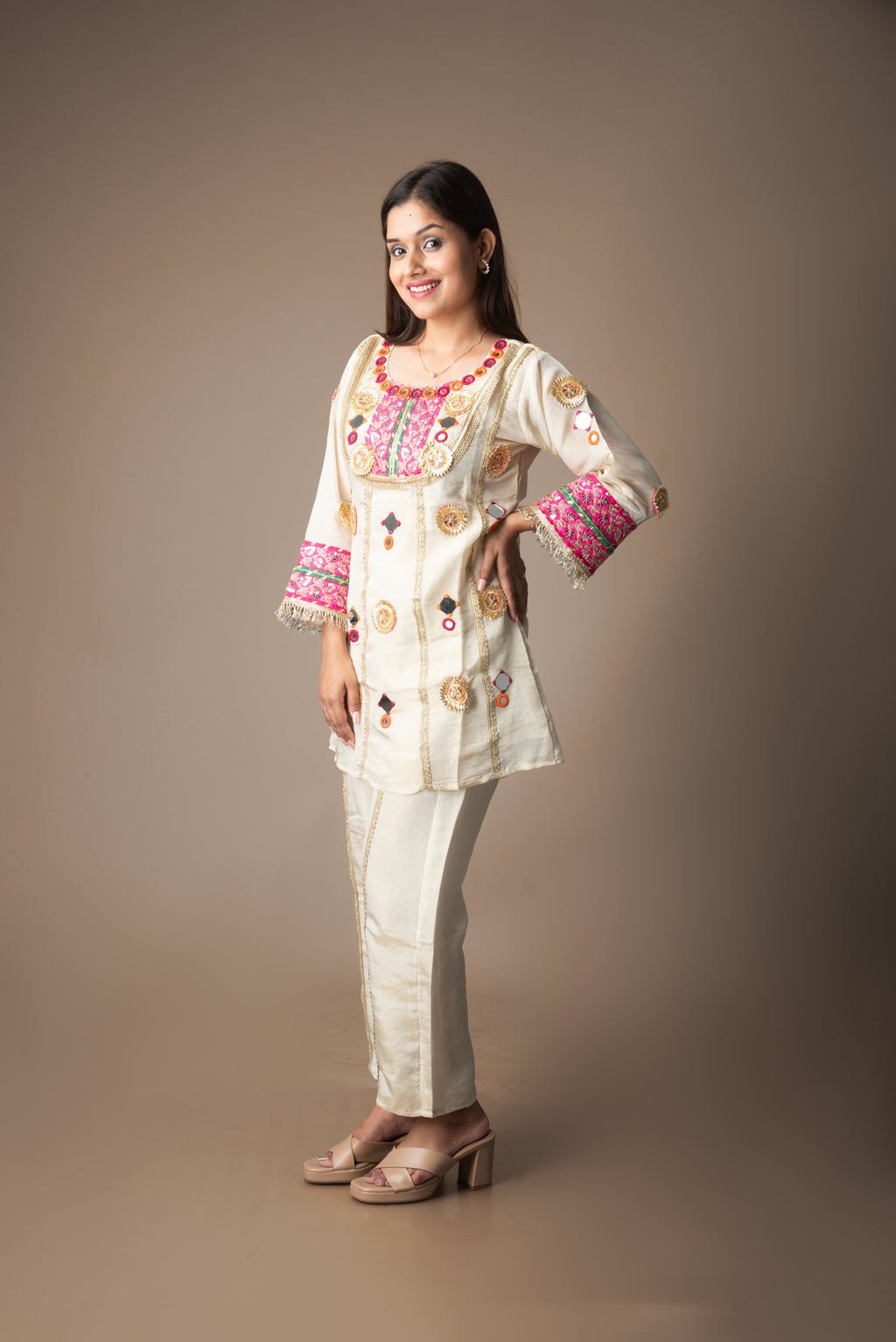 Woman wearing a traditional embroidered outfit on a plain background