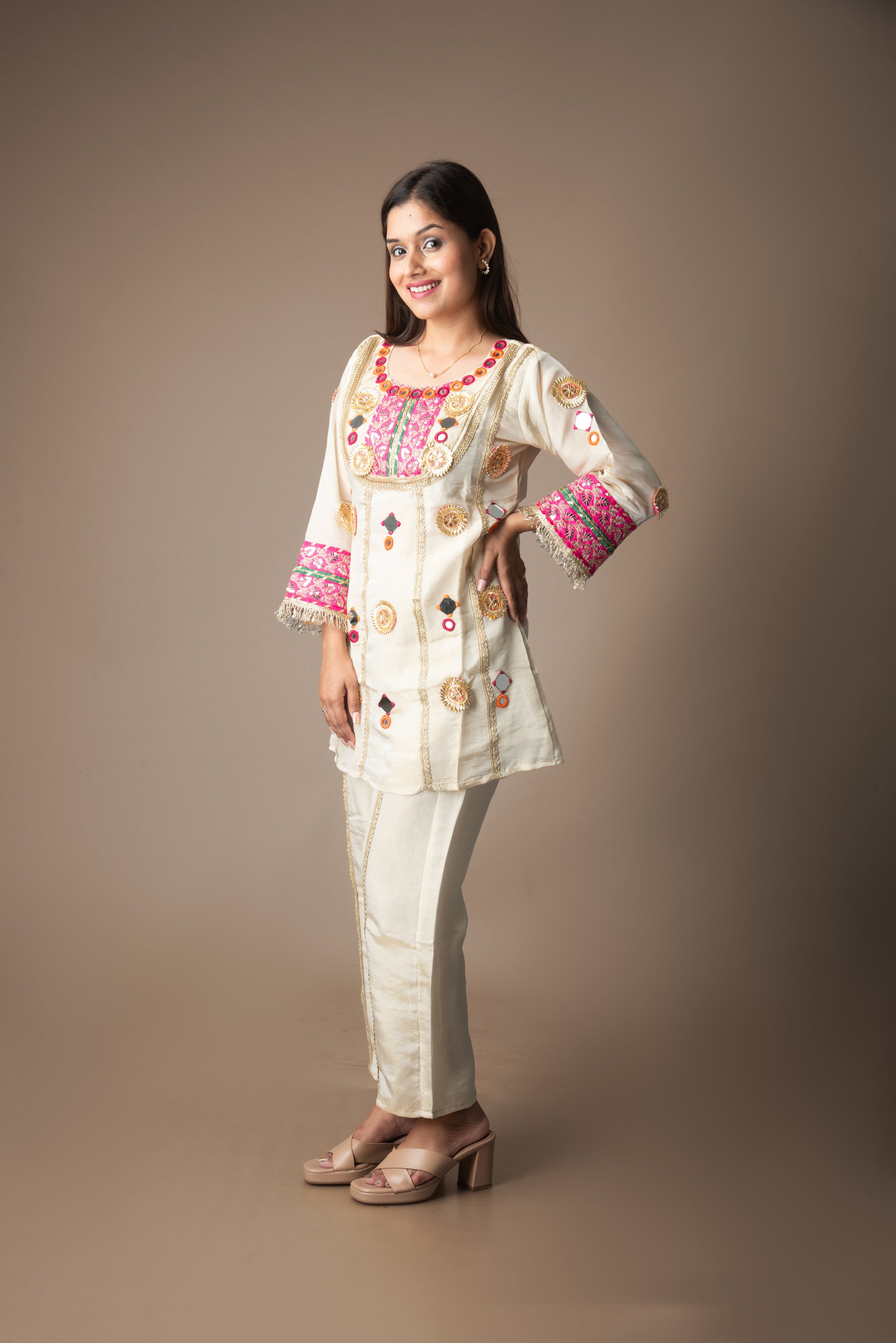 Woman wearing a traditional embroidered outfit on a plain background