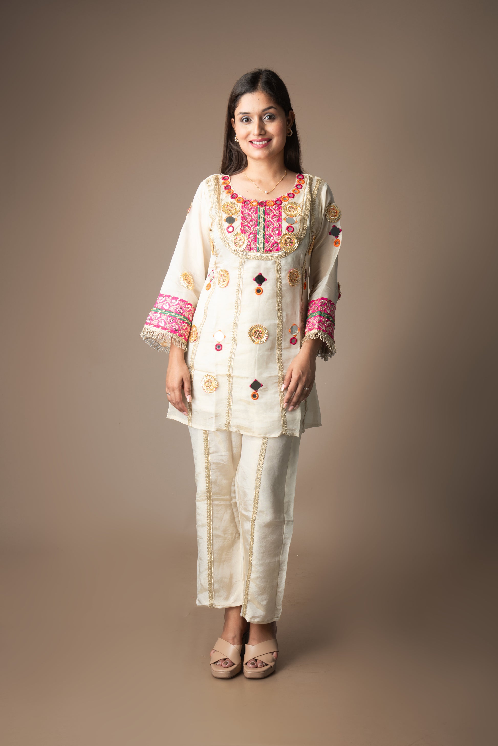 Woman wearing a traditional embroidered outfit on a plain background