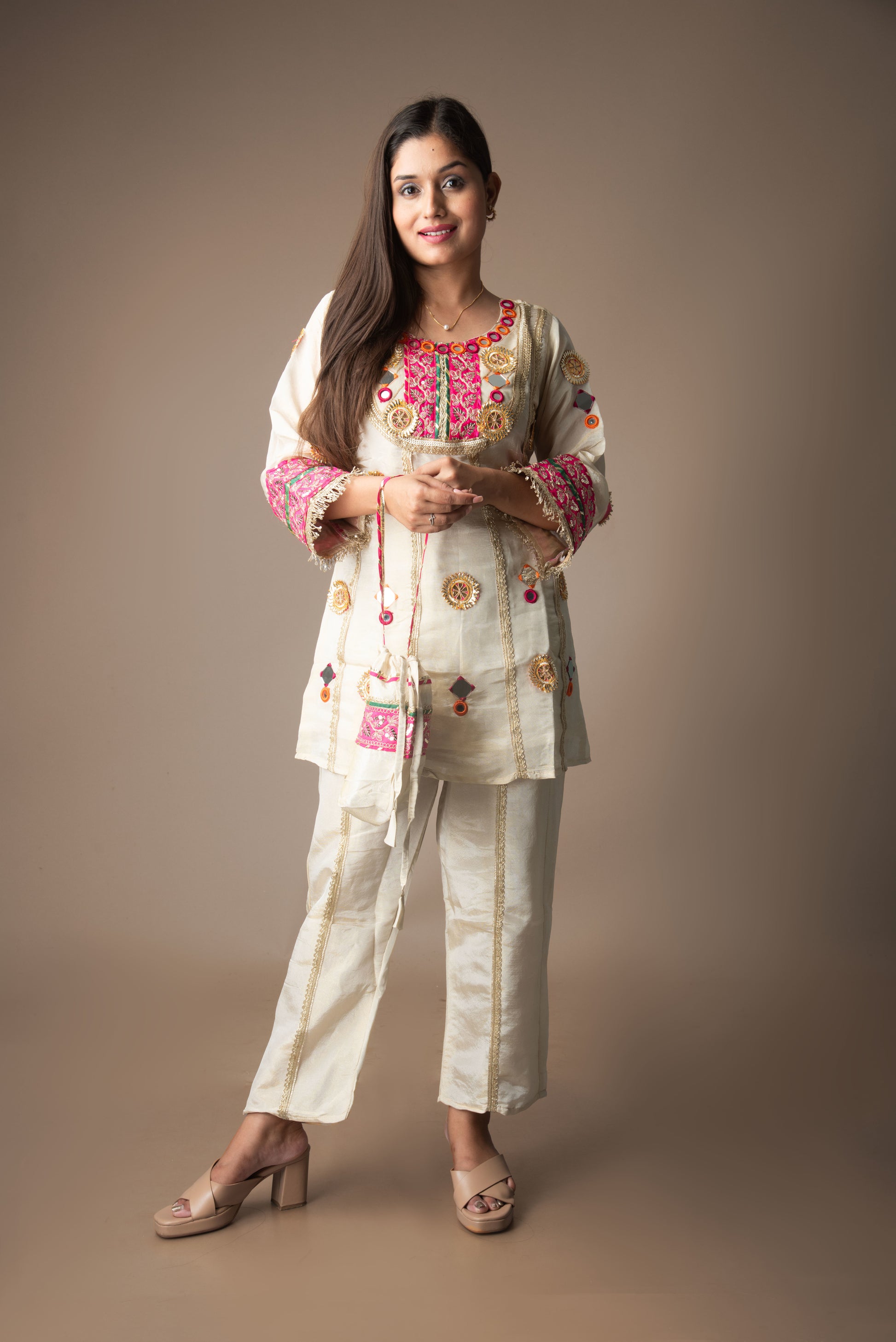 Woman wearing a traditional embroidered outfit on a plain background