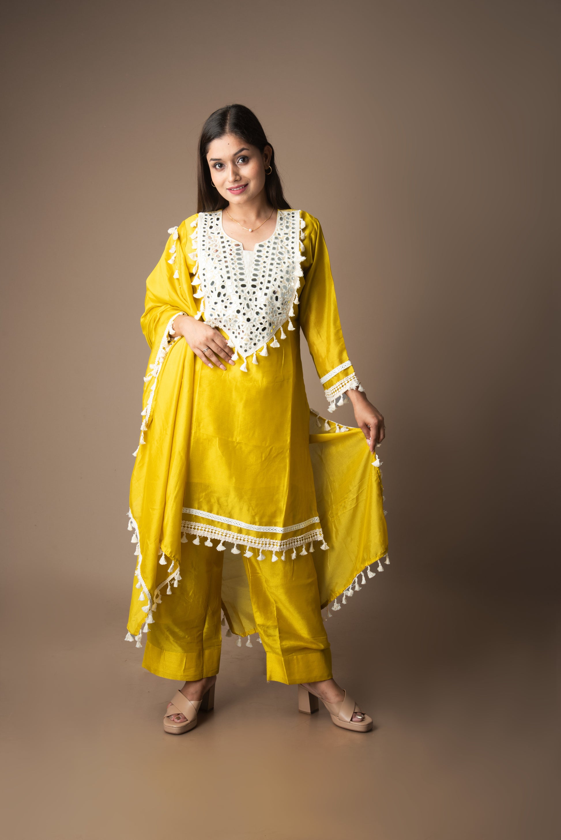 Woman wearing a yellow traditional outfit with white patterns on a brown background