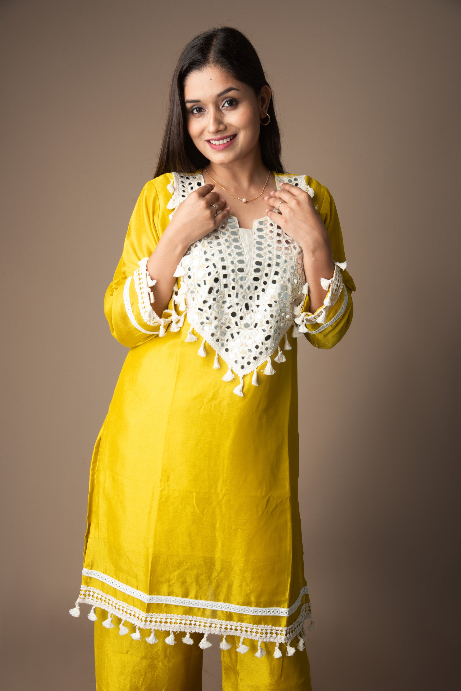 Woman wearing a yellow dress with white lace details on a brown background
