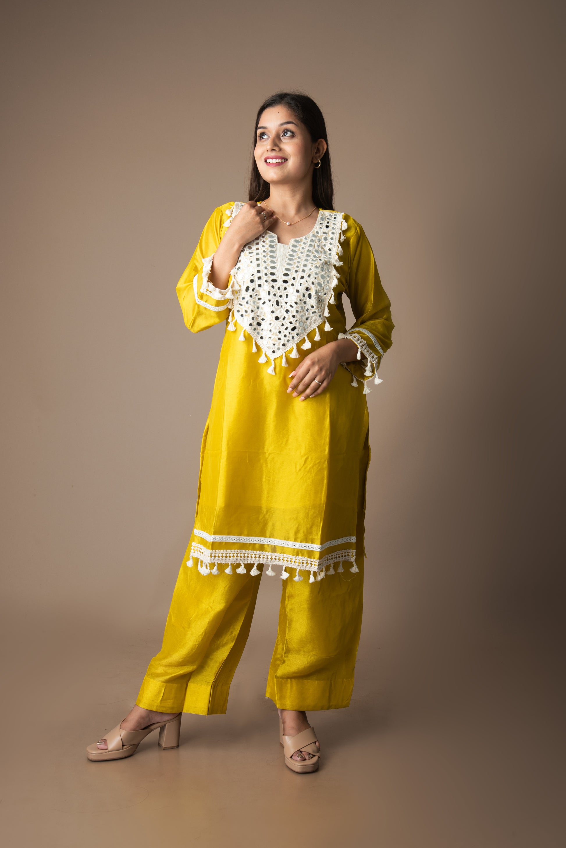 Woman wearing a yellow traditional outfit with white lace details on a brown background