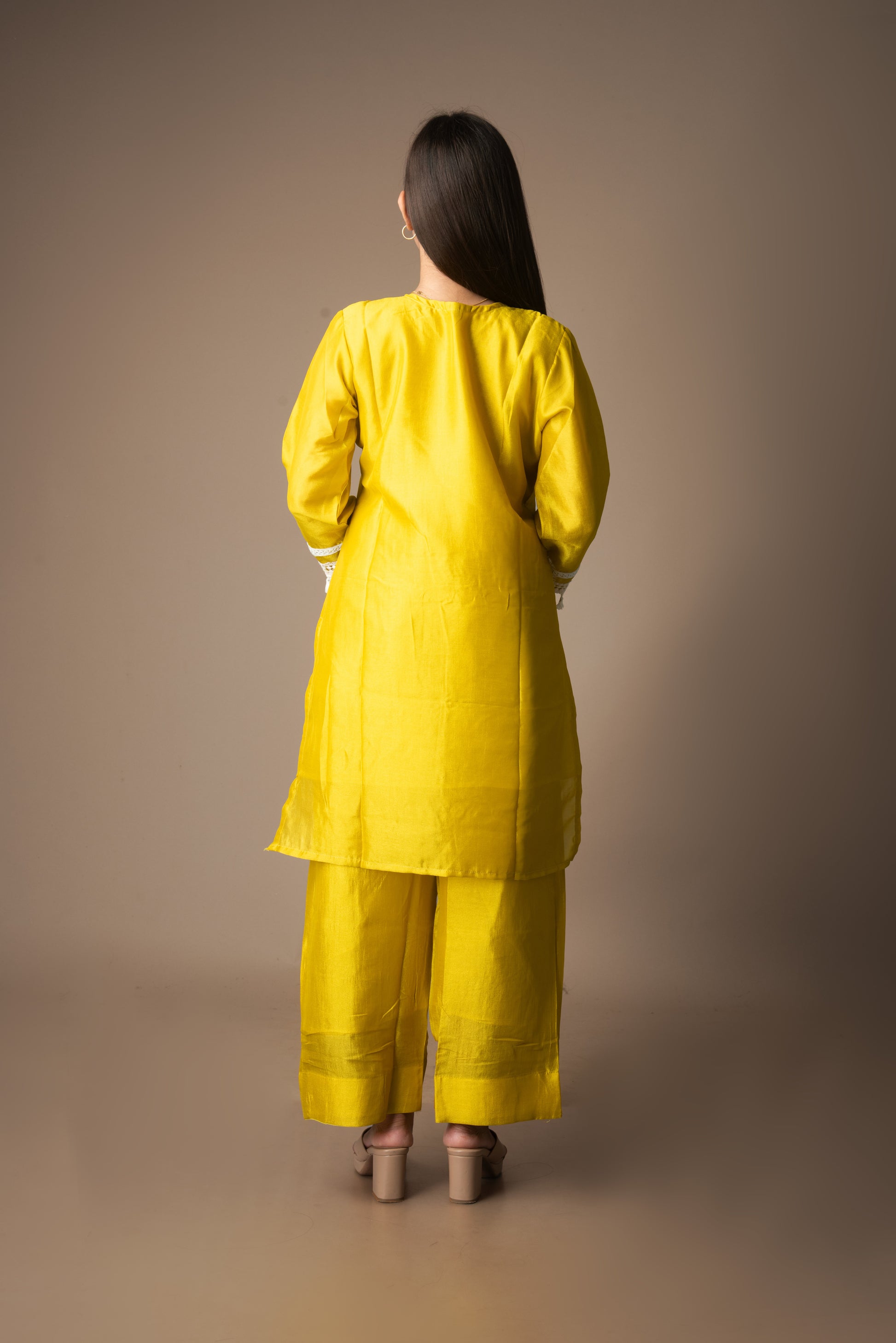 Woman wearing a yellow traditional outfit against a brown background