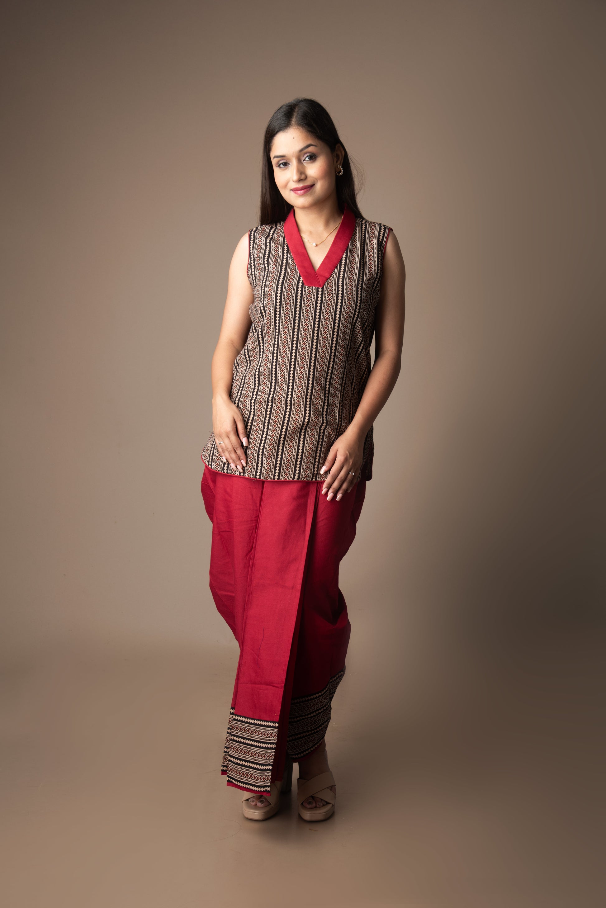 Woman wearing a sleeveless striped top and red pants against a brown background