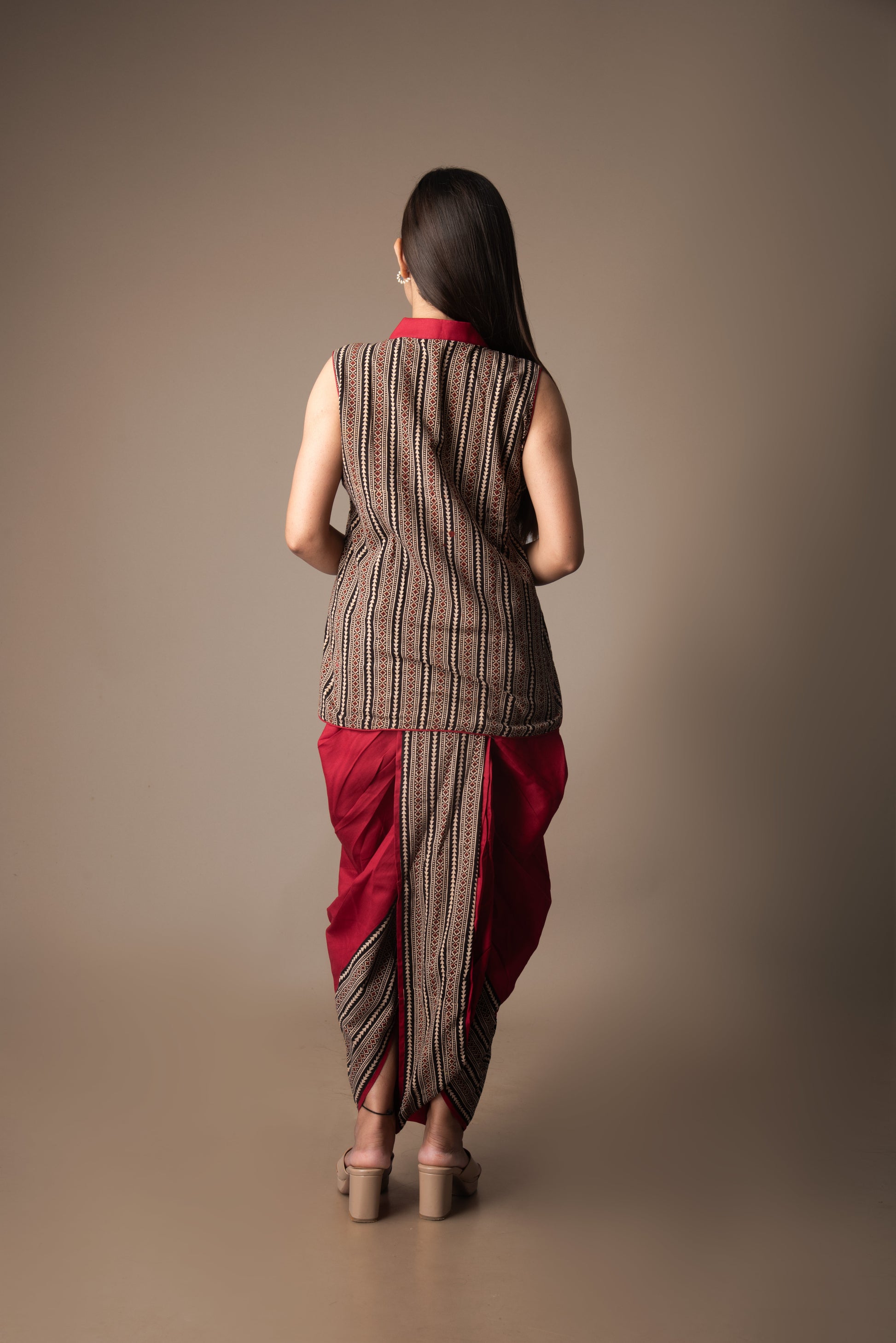 Woman wearing a traditional outfit with a brown and red patterned dhoti on a beige background